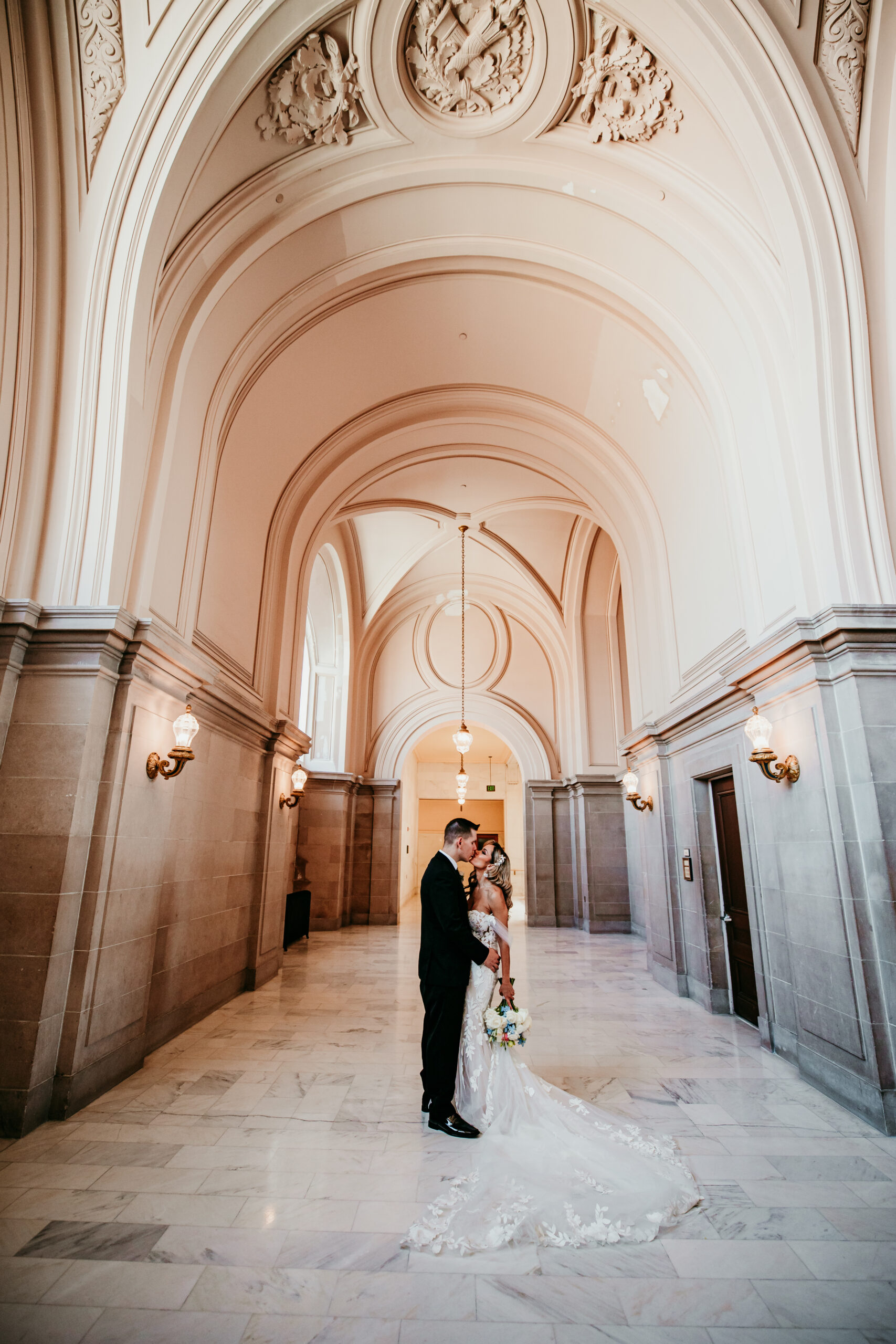 Bride and groom sharing a quiet moment beneath the grand arches for romantic San Francisco City Hall elopement photos and tips, captured by a San Francisco elopement photographer.