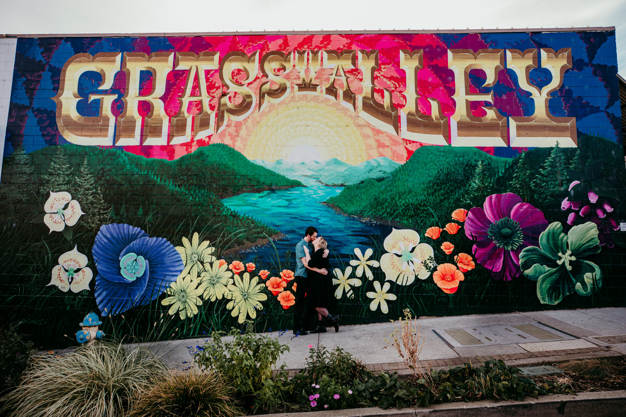 Elopement couple shares a kiss in front of the colorful “Grass Valley” mural in downtown Grass Valley, California.