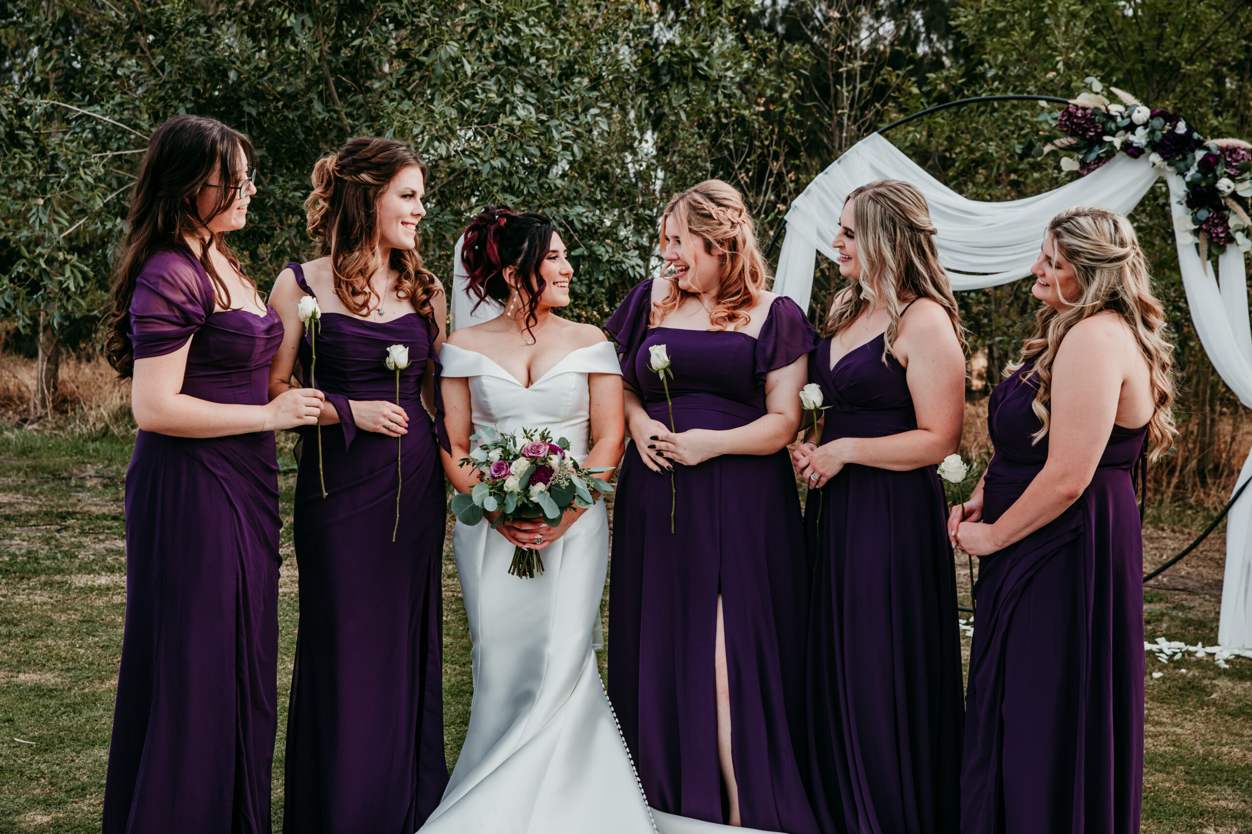 Bride and bridesmaids in purple dresses sharing a joyful moment after the ceremony at a fall wedding in Vacaville, CA