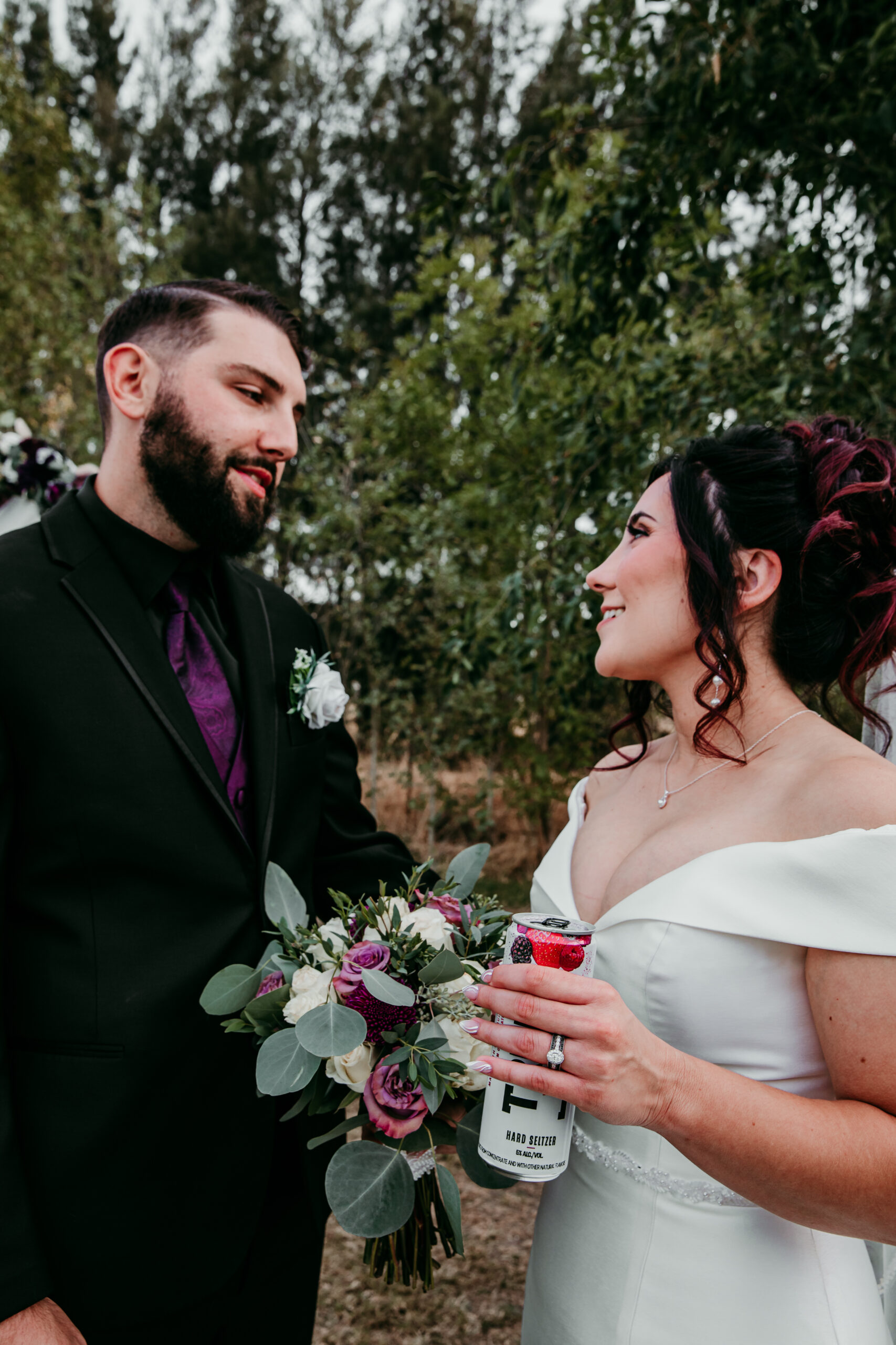 Bride and groom sharing a sweet moment post-ceremony with bouquet and drinks in hand at their fall backyard wedding in Vacaville, CA