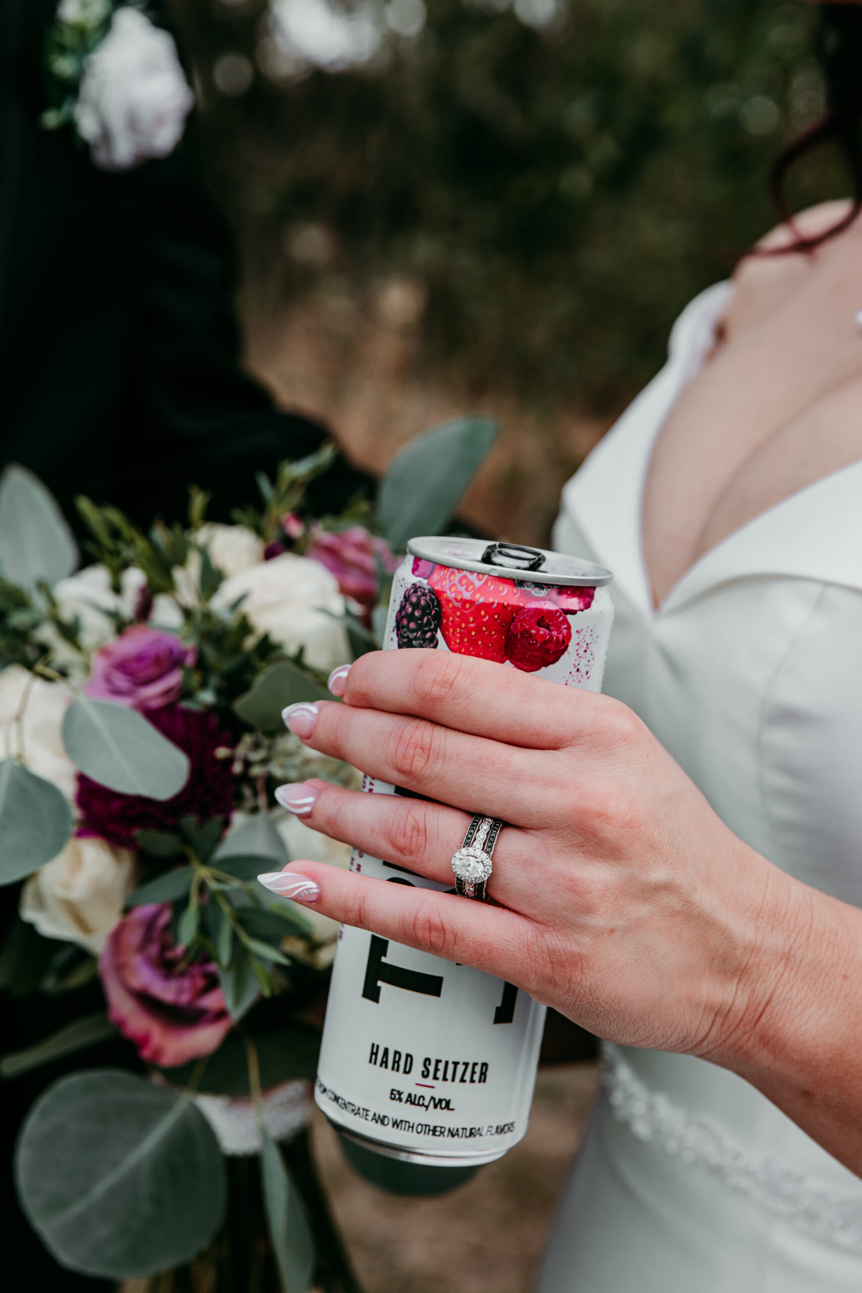 Close-up of bride’s hand holding a hard seltzer, with bouquet and wedding ring in focus at a fall Bay Area wedding