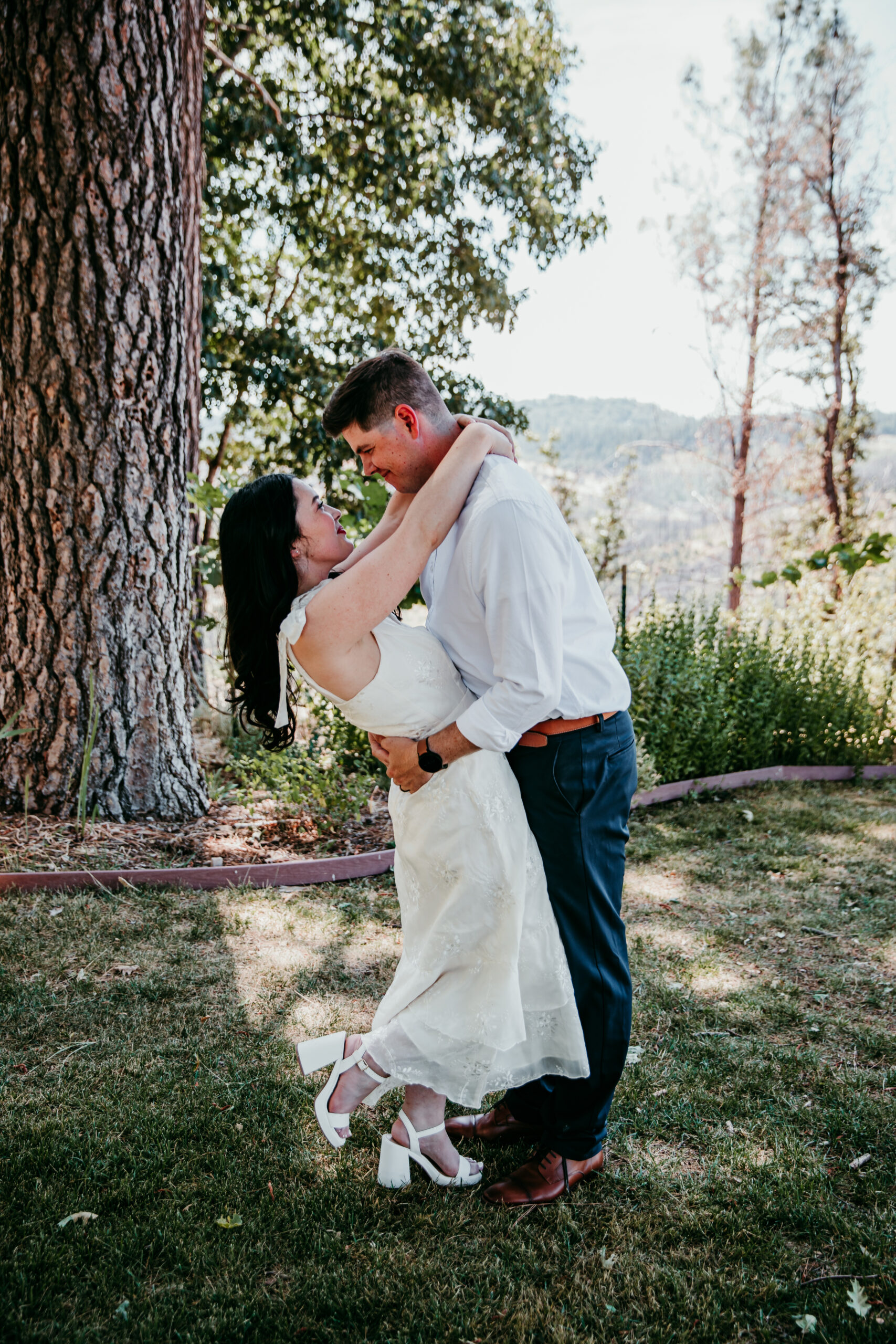 Bride and groom embracing under the trees during their Northern California elopement at a peaceful Airbnb with mountain views.