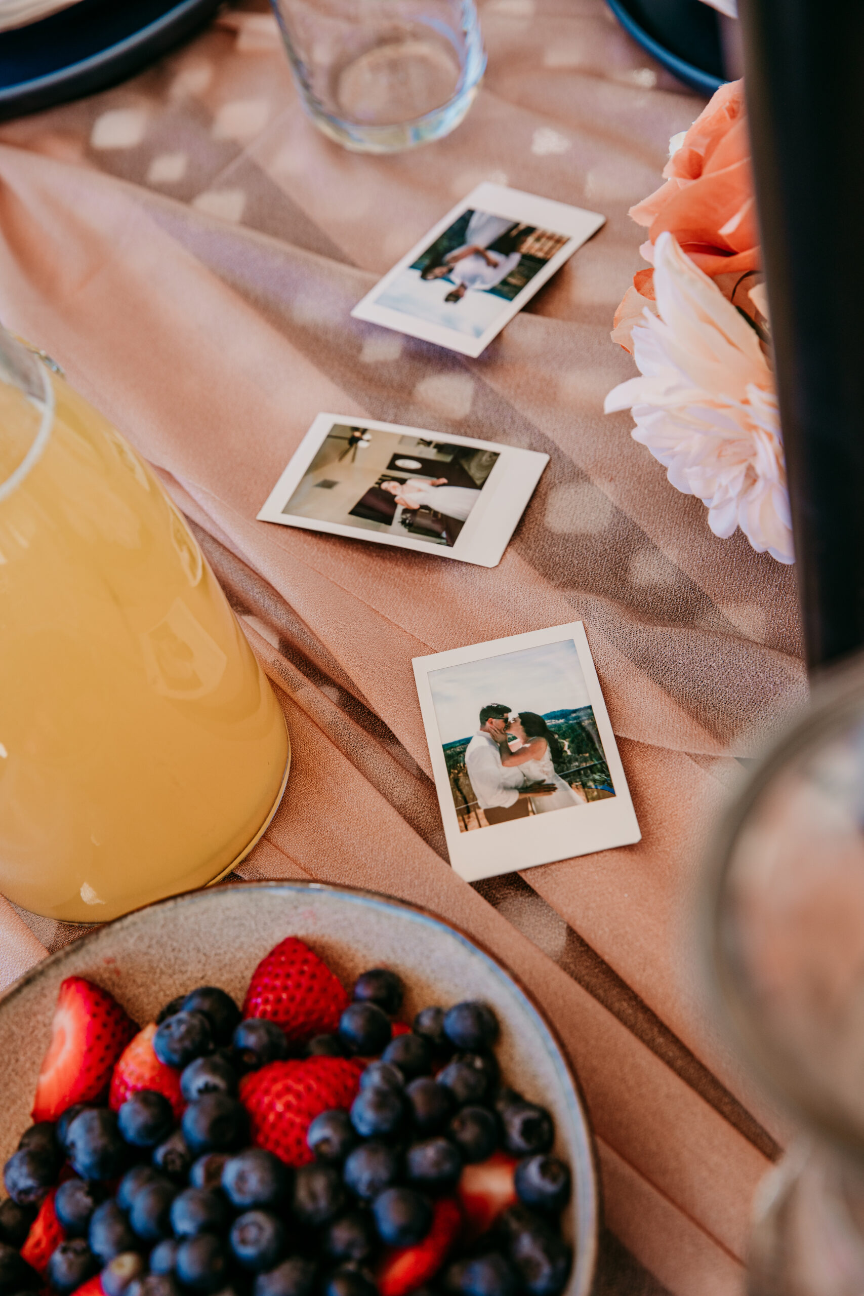 Polaroid photos on a brunch table with fresh fruit and orange juice at a Northern California Airbnb elopement.