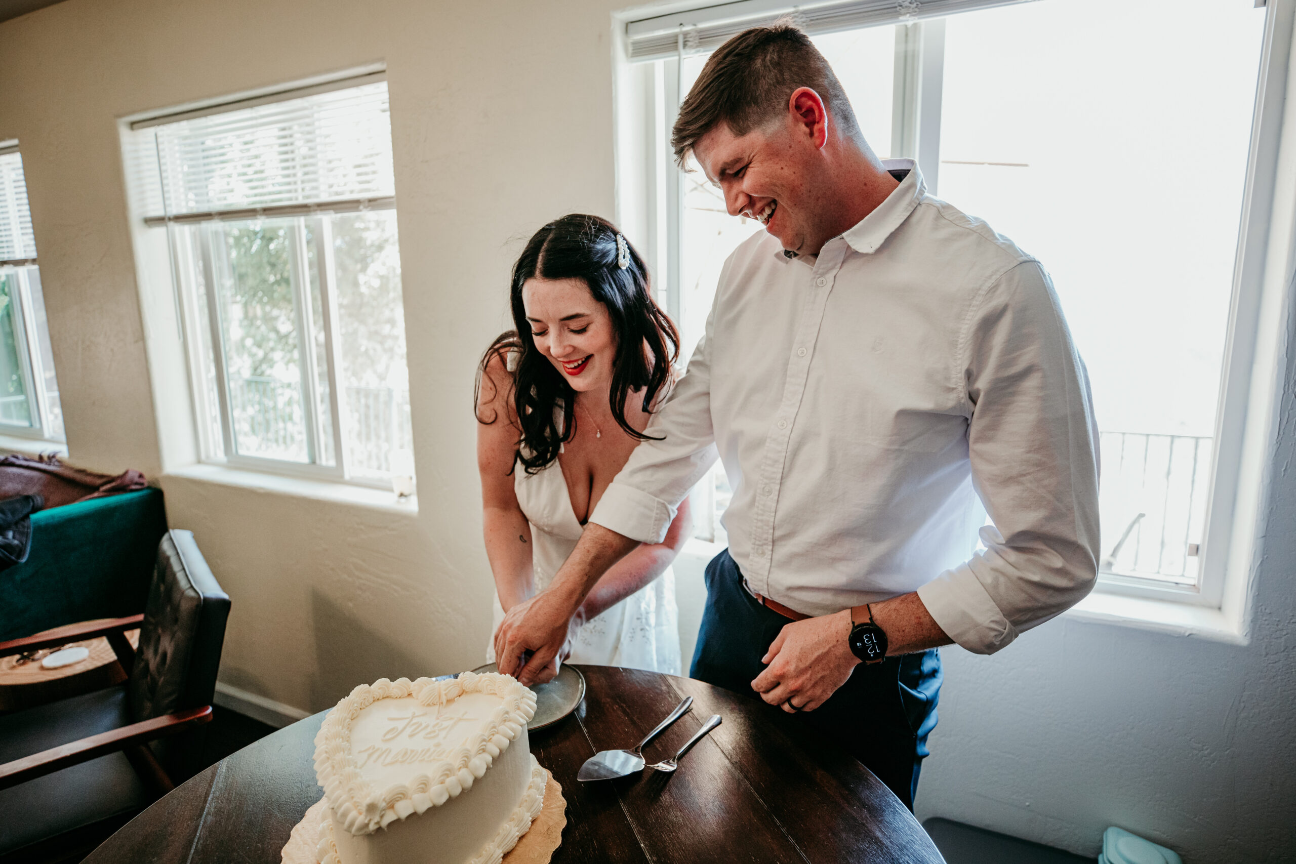 Bride and groom laughing together while cutting their wedding cake during a lighthearted Northern California elopement celebration.