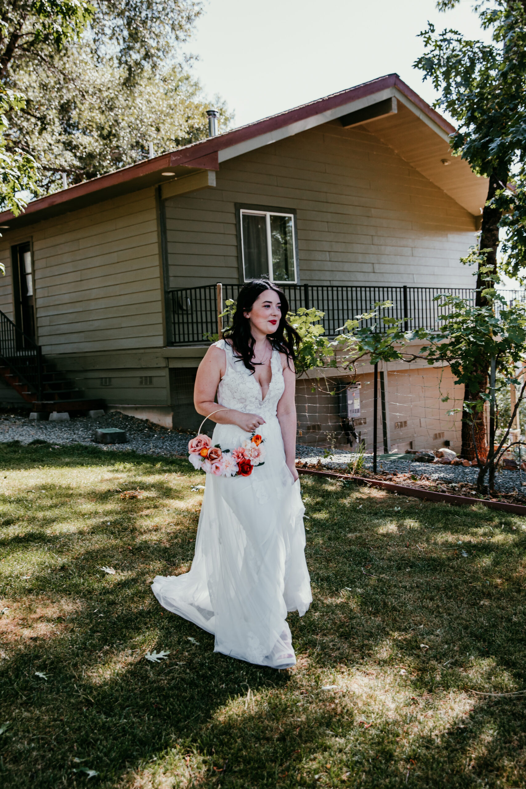 Bride walking through the Airbnb backyard holding a bright bouquet during her Grass Valley CA elopement.