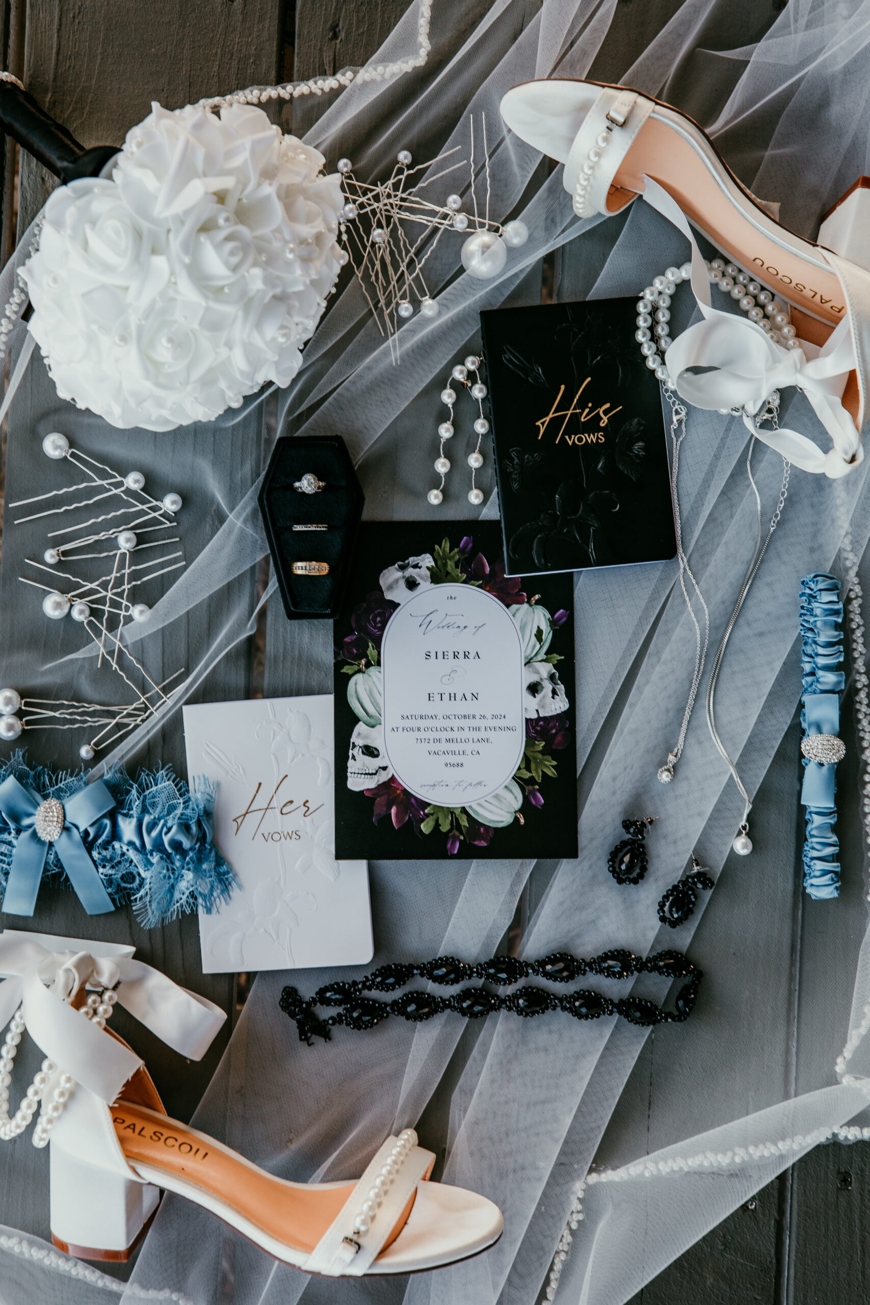 Flat lay of wedding details with vow books, white heels, hair pins, and accessories styled with fall-inspired accents