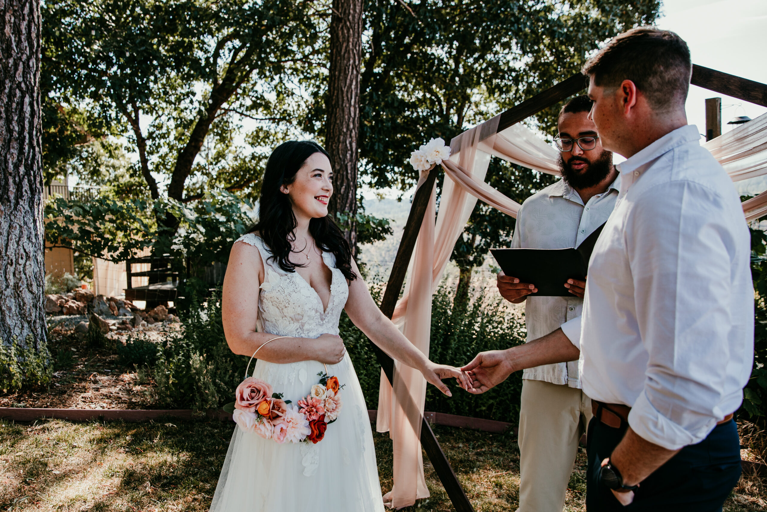 Bride smiling and holding groom’s hand during their backyard Airbnb ceremony in Grass Valley CA, captured by a Grass Valley CA elopement photographer.