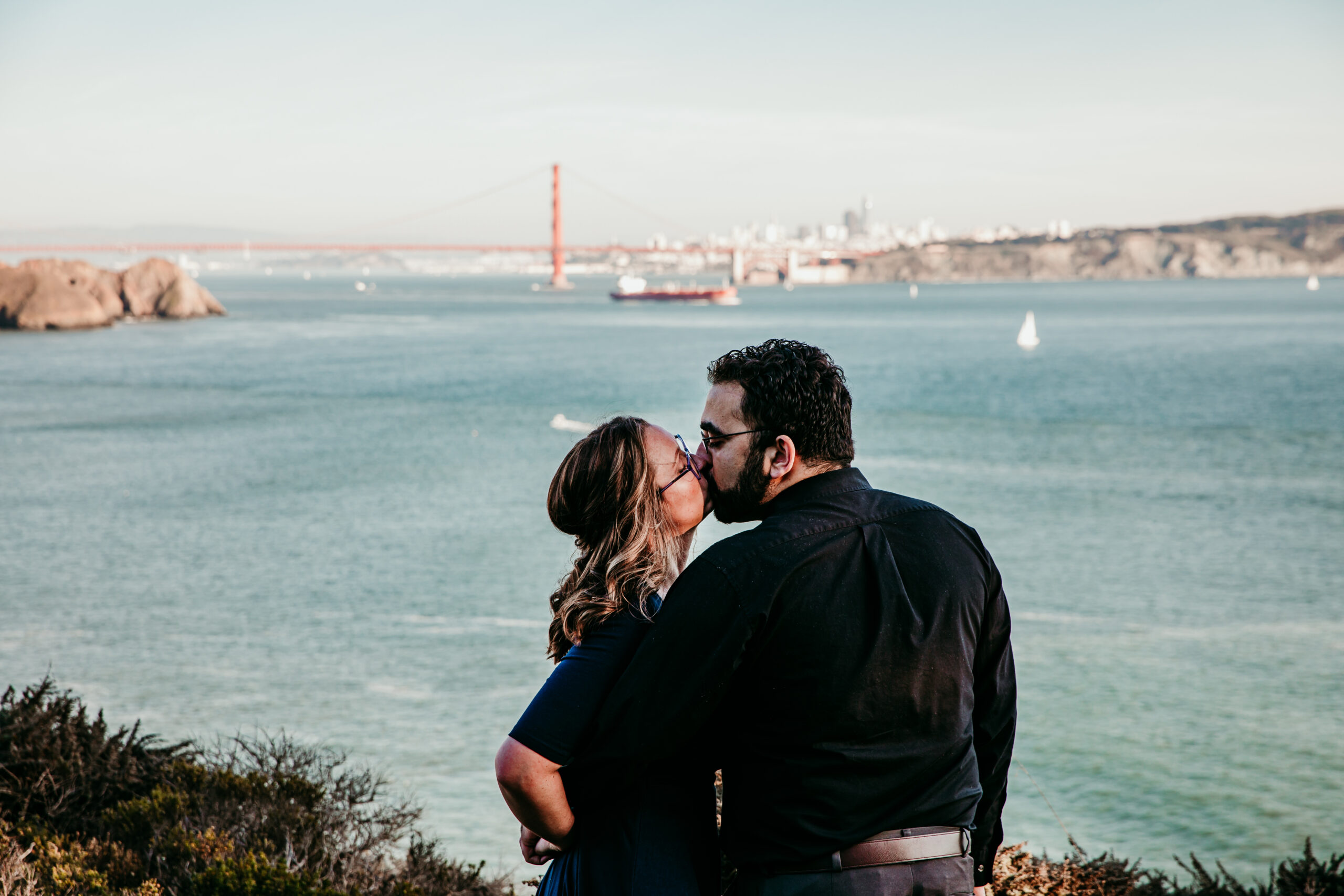 Couple sharing a kiss with the Golden Gate Bridge in the background, a classic and scenic spot for getting married in California.