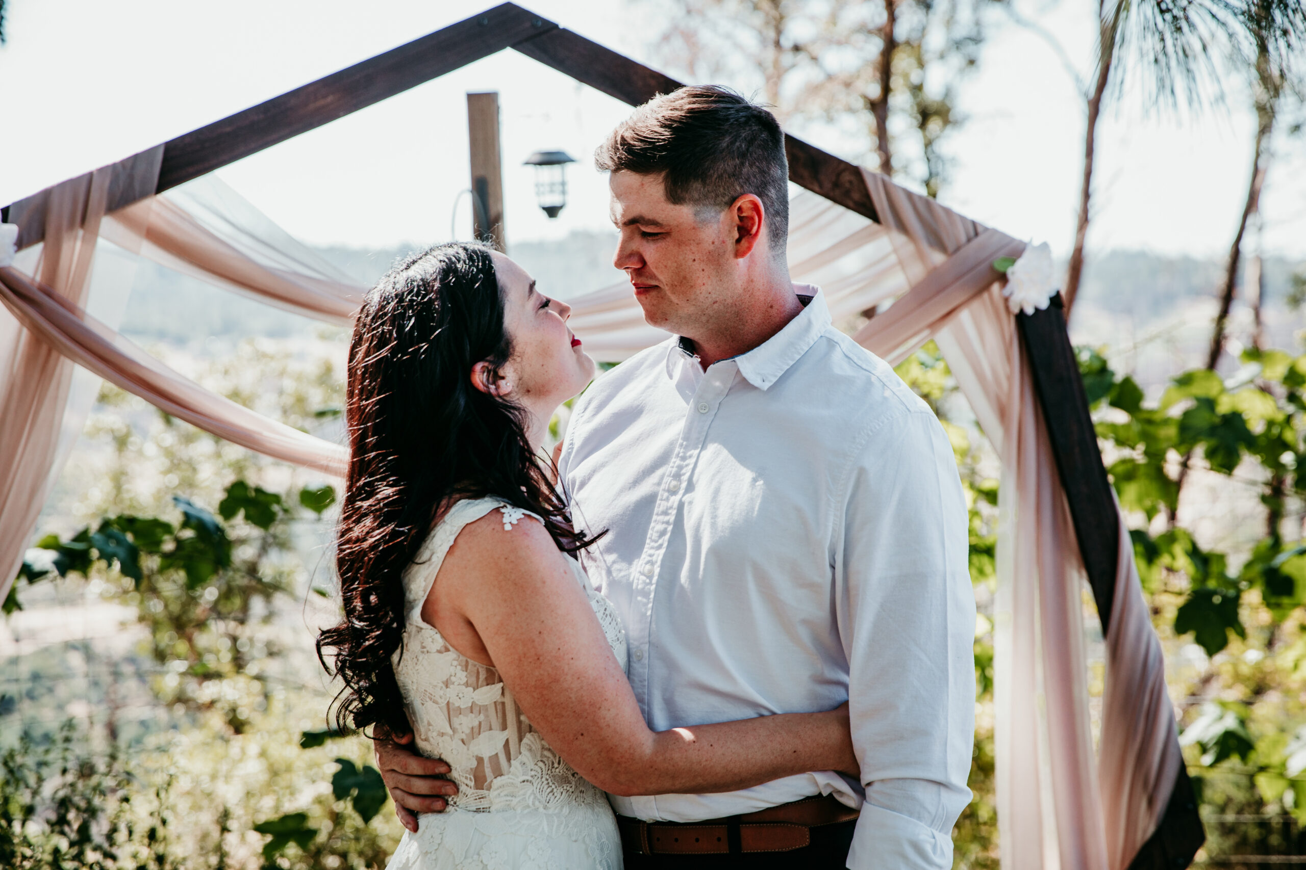 Bride and groom holding each other under a wooden arch during their Northern California elopement at a peaceful Airbnb setting.