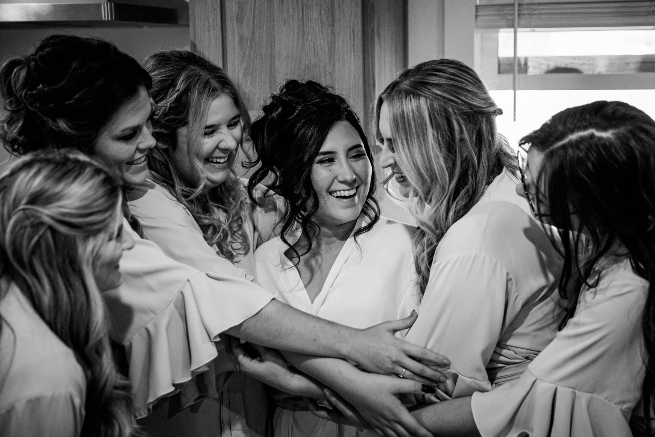 Black and white photo of bride laughing with her bridesmaids while getting ready on her wedding day in Vacaville, captured by Bay Area wedding photographer