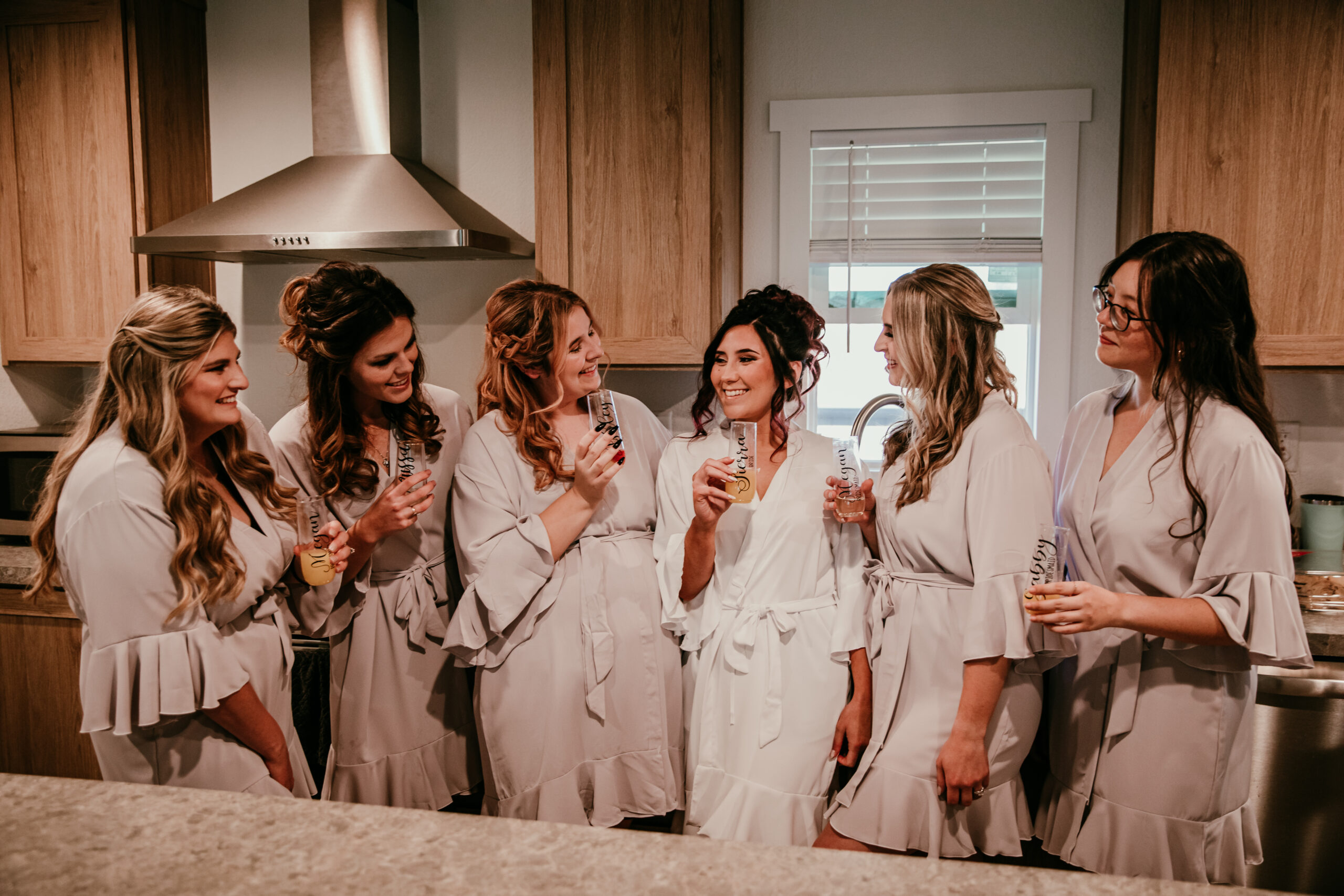 Bride and bridesmaids in matching robes sharing a toast before the ceremony at a cozy backyard wedding in Vacaville, CA