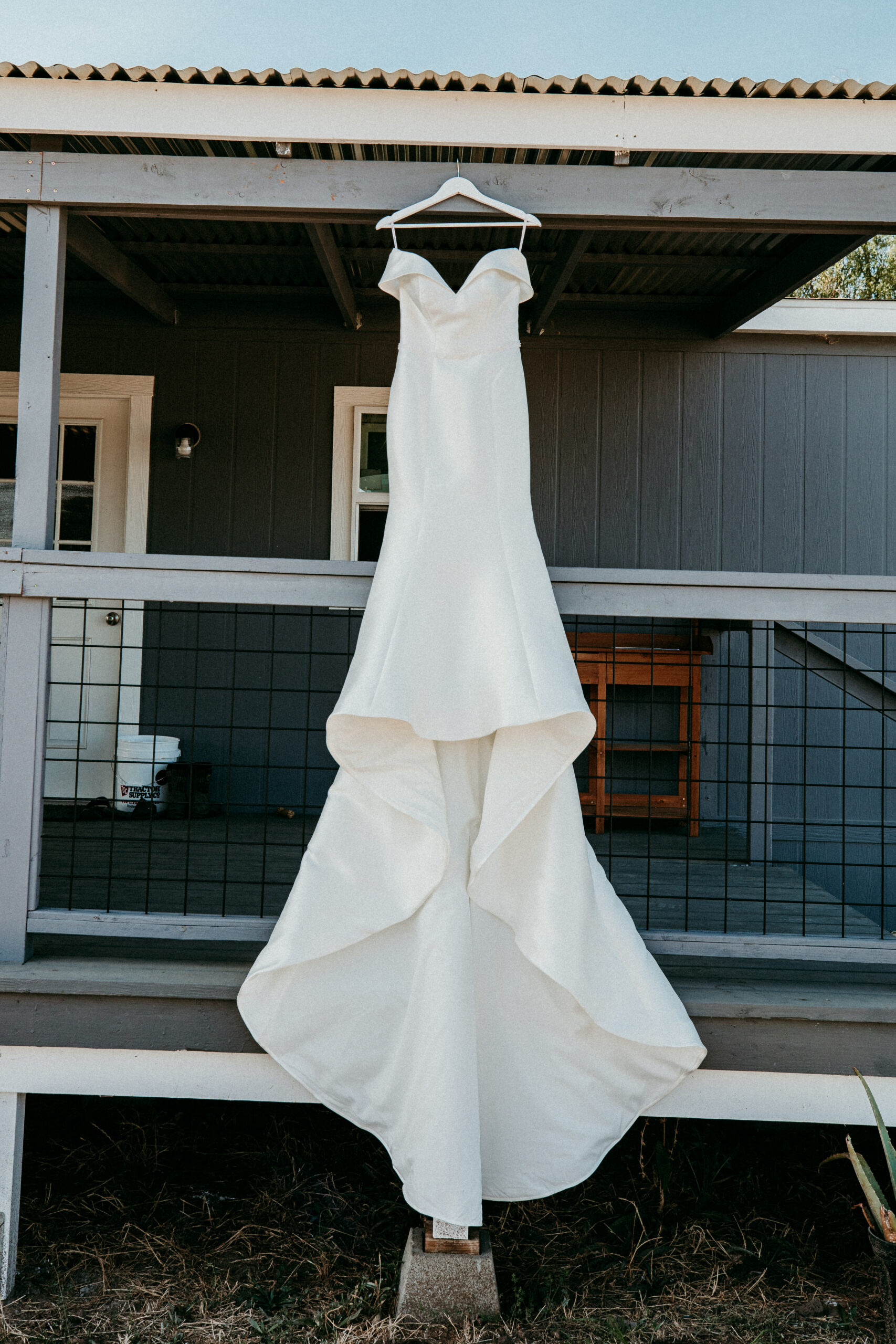 Elegant white wedding dress hanging on a porch before backyard wedding in Vacaville, CA, photographed by Bay Area wedding photographer