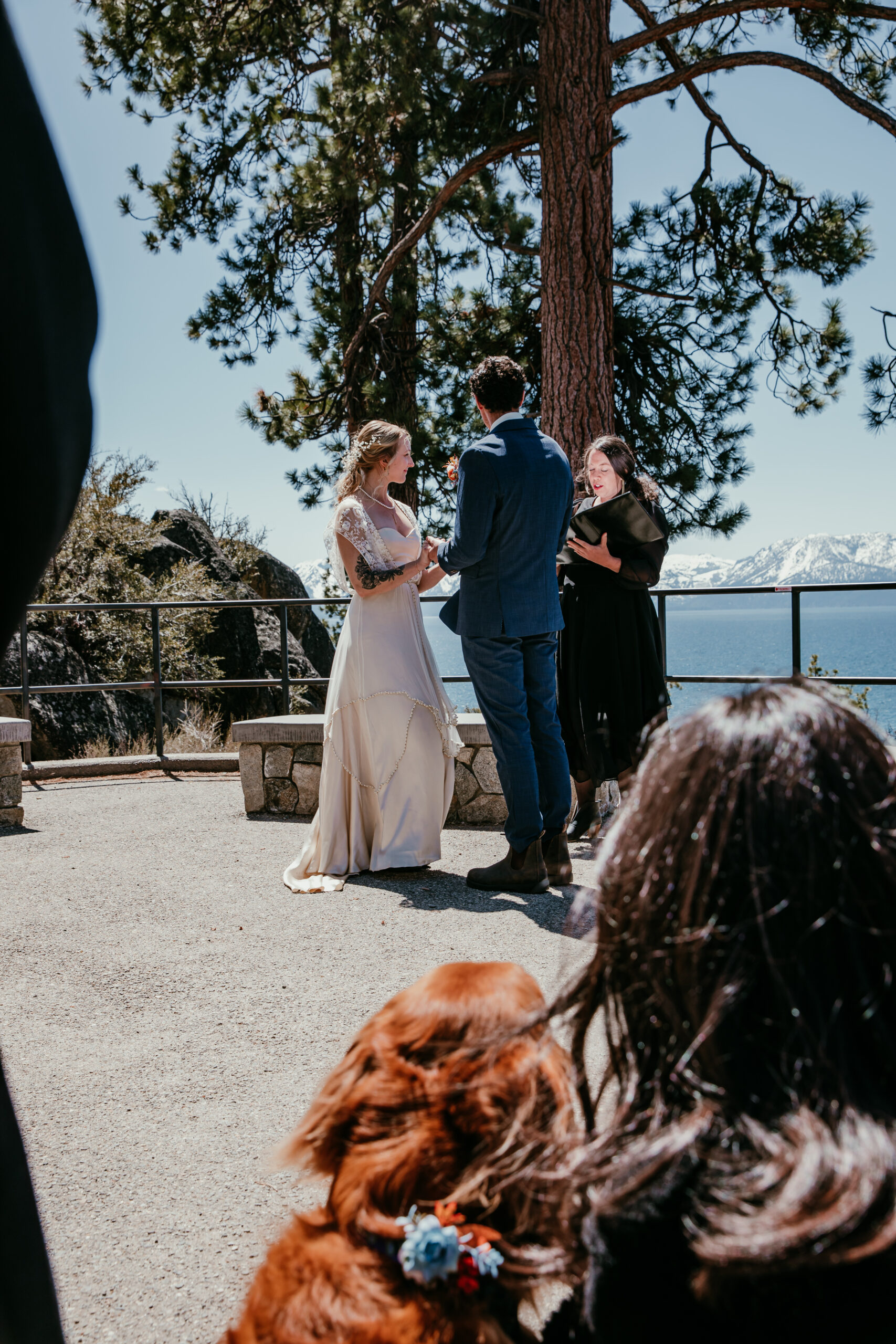 Couple exchanging vows with Lake Tahoe in the background while their golden retriever watches during their Logan Shoals Vista Point elopement