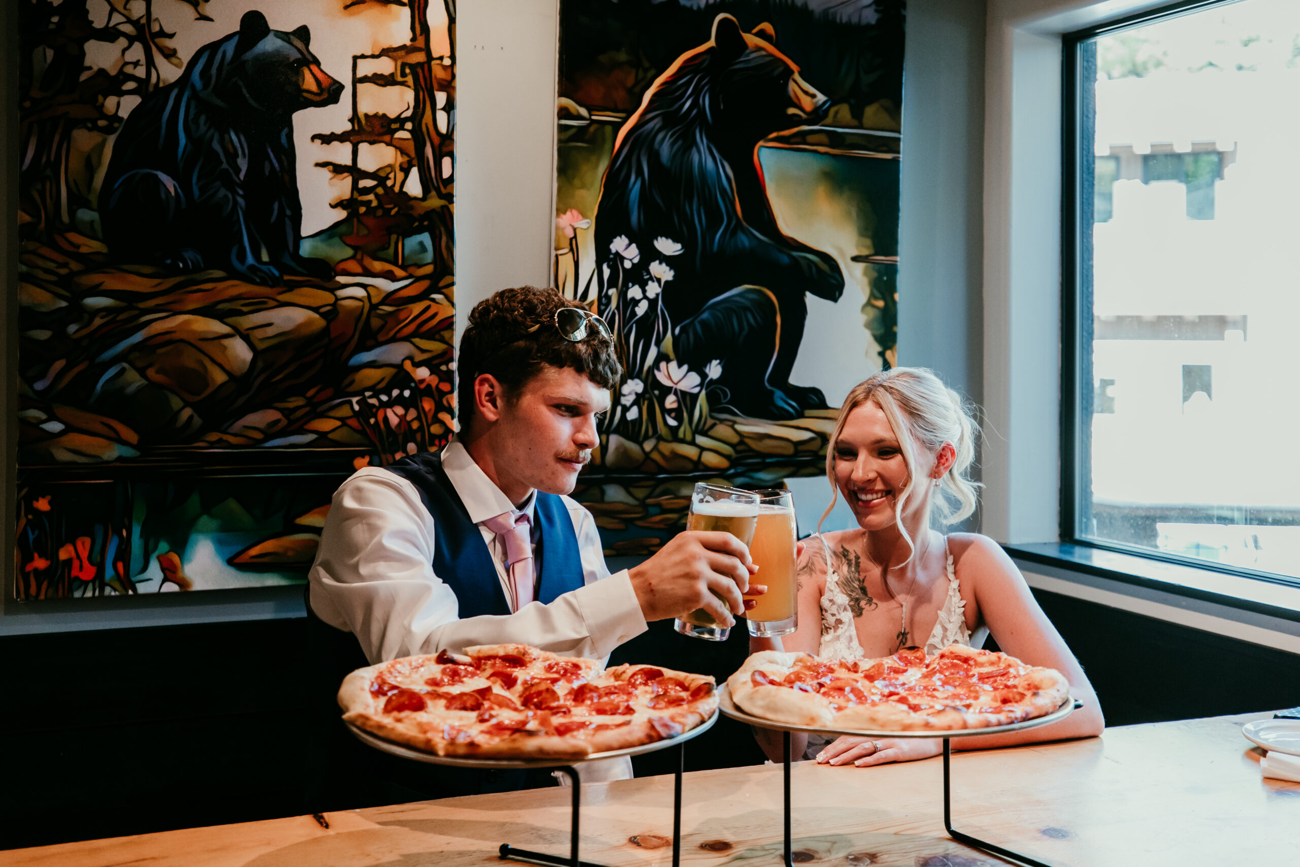 Couple celebrating their Mount Shasta elopement with pizza and a toast at a local restaurant after their ceremony.