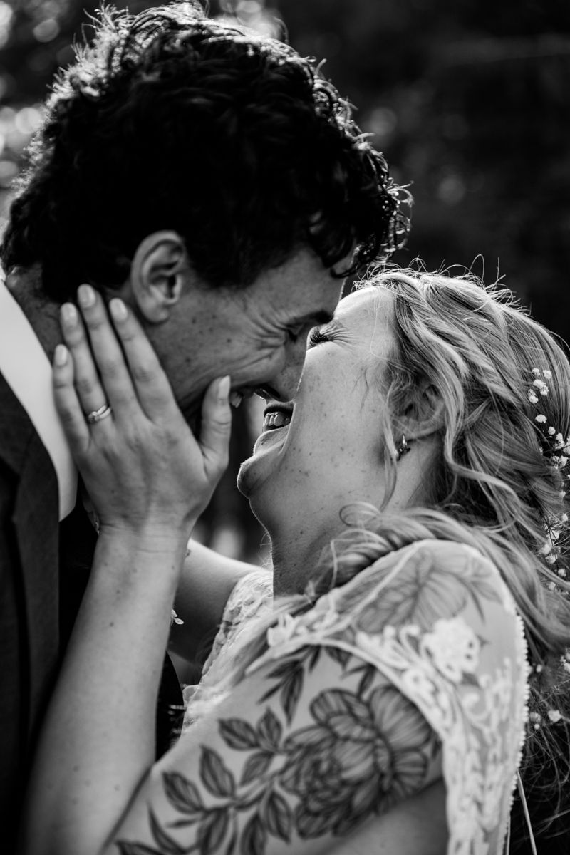 Black and white close-up of bride and groom laughing and embracing during their Truckee elopement, hands on each other’s faces in a joyful moment.