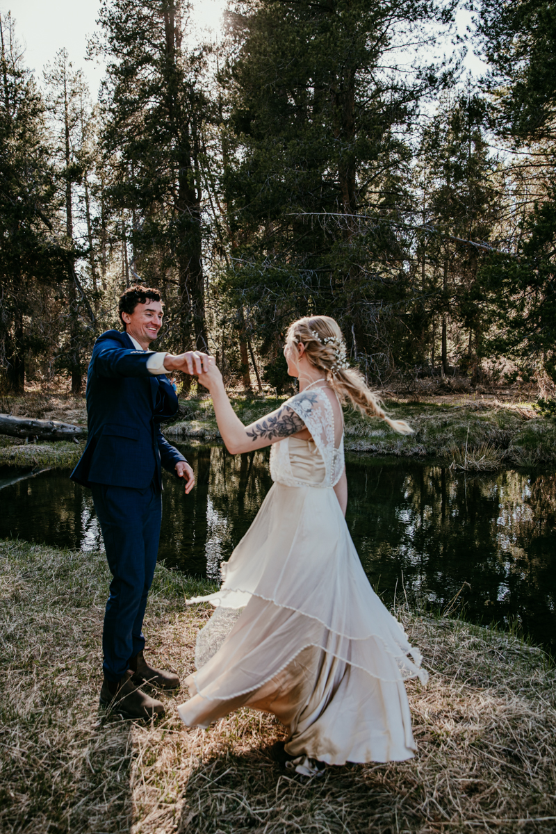 Bride and groom twirl together in a forest clearing near a quiet creek in Truckee, California during their intimate elopement.