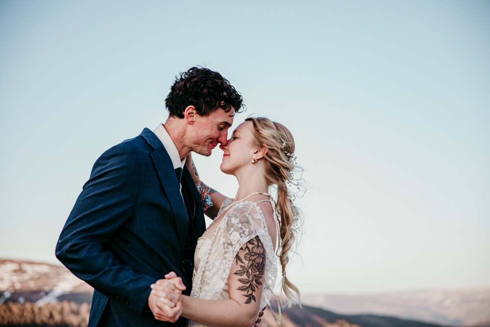 Bride and groom sharing an intimate moment, touching foreheads and holding hands during their mountain elopement in Donner Summit with soft sunset lighting.