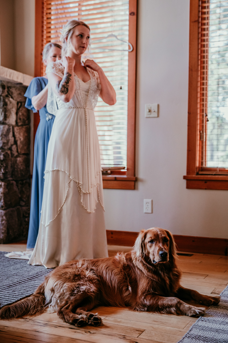 Bride getting ready with help from her mom while their golden retriever lays on the floor nearby