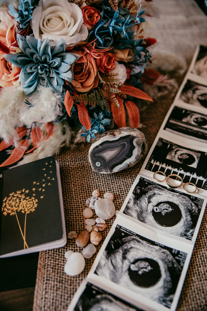 Flat lay of bouquet, ultrasound photos, wedding rings, and keepsakes symbolizing the couple’s elopement and growing family