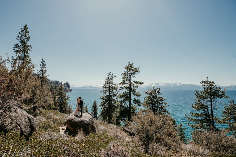Newlyweds standing on a boulder overlooking Lake Tahoe during their Logan Shoals Vista Point elopement