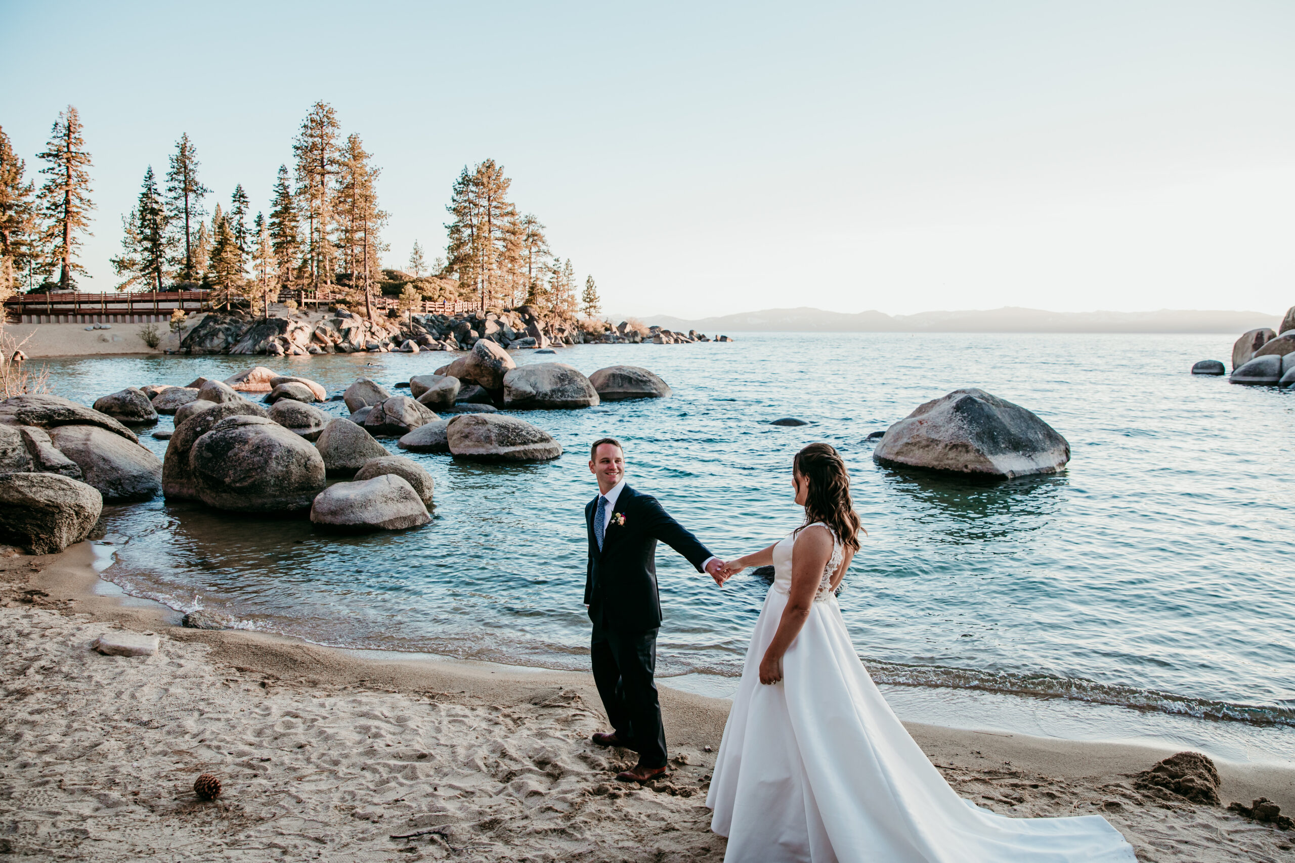 Bride and groom holding hands along the shoreline at Sand Harbor—how to get married at Sand Harbor for a romantic and scenic Lake Tahoe elopement.