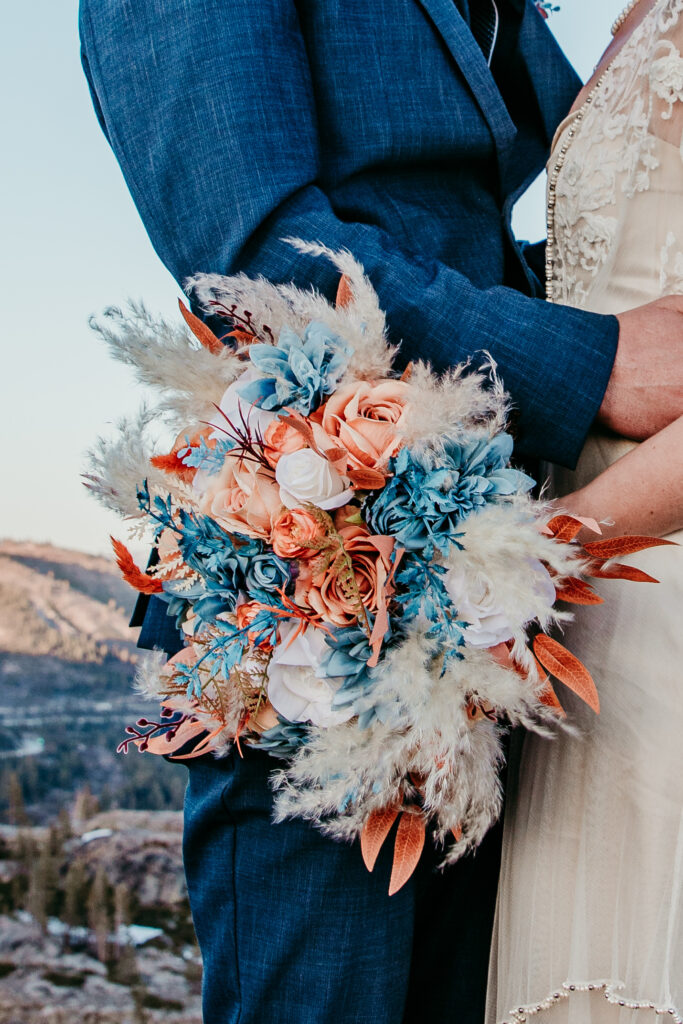Close-up of bride holding colorful fabric floral bouquet during her forest elopement, showing that even in the woods, you can have intentional and beautiful wedding details.