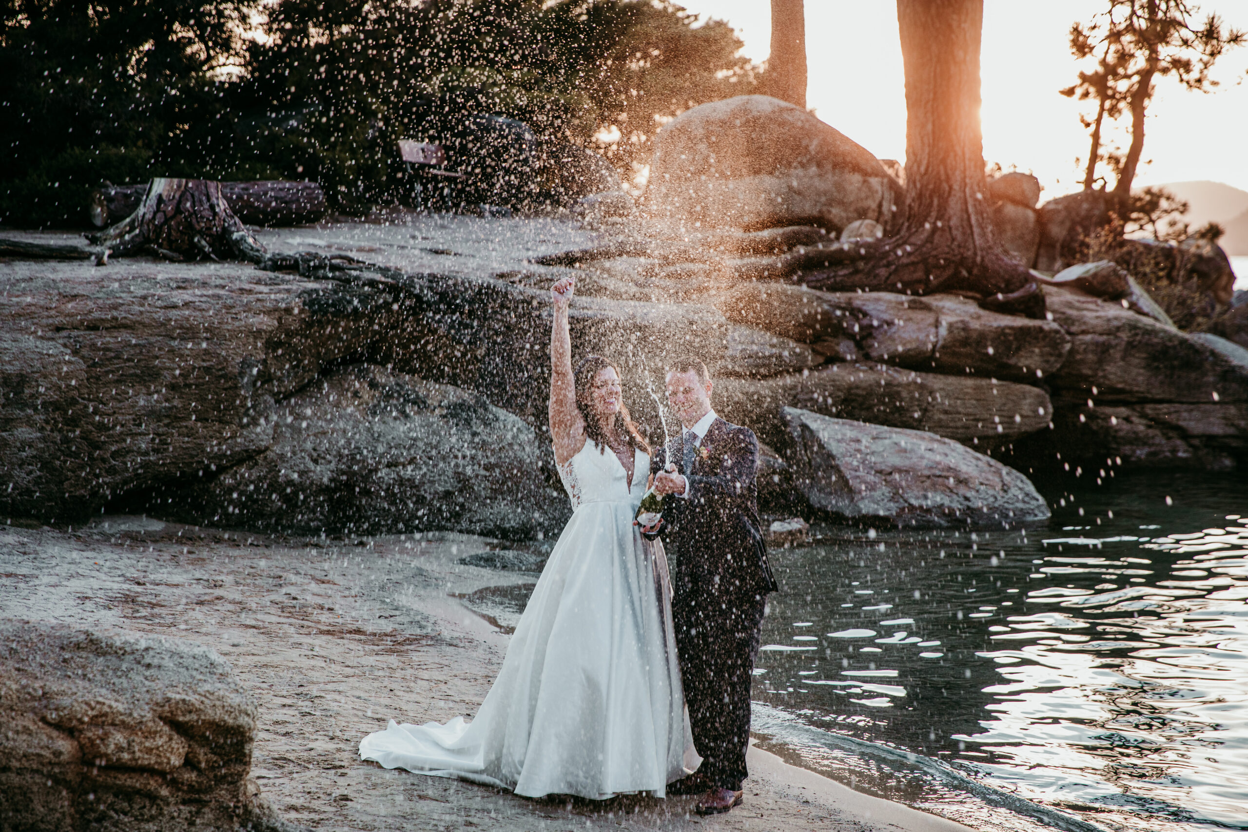 Just married couple spraying champagne at sunset on the beach at Sand Harbor, a fun and scenic choice for where to elope in California.