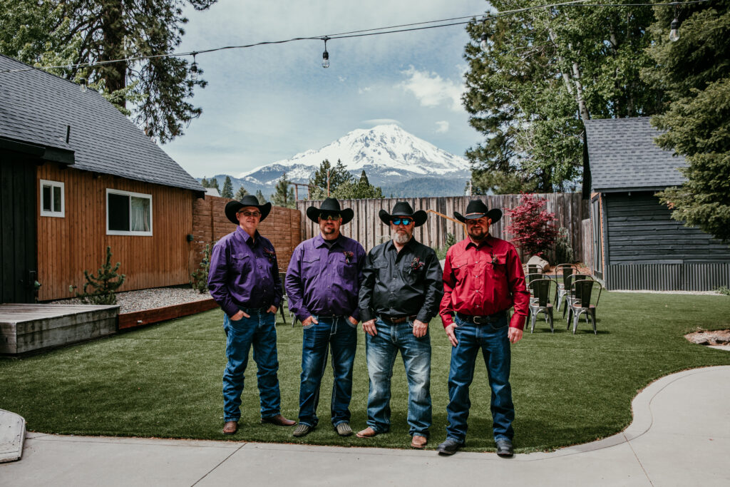 Groom and groomsmen in western attire standing in front of Mount Shasta at Shasta View Lodge while eloping in Mount Shasta.