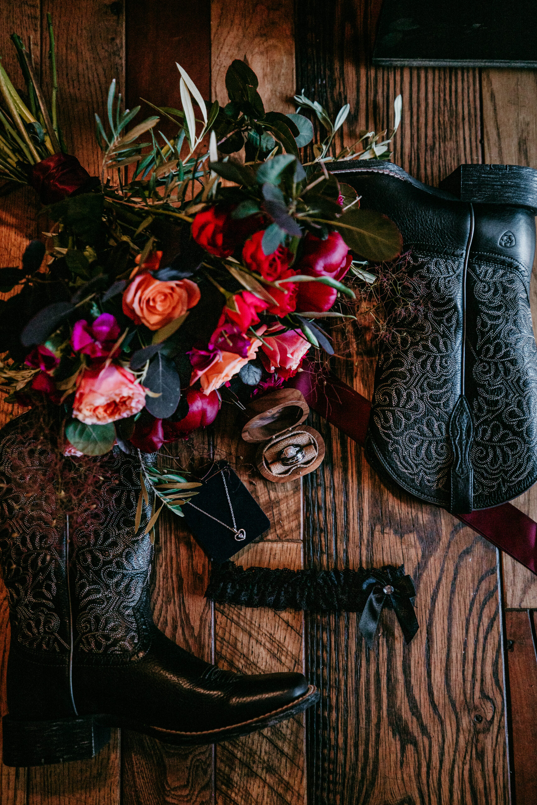 Flat lay of wedding day details including a floral bouquet, cowboy boots, rings, garter, and jewelry—captured before eloping in Mount Shasta.