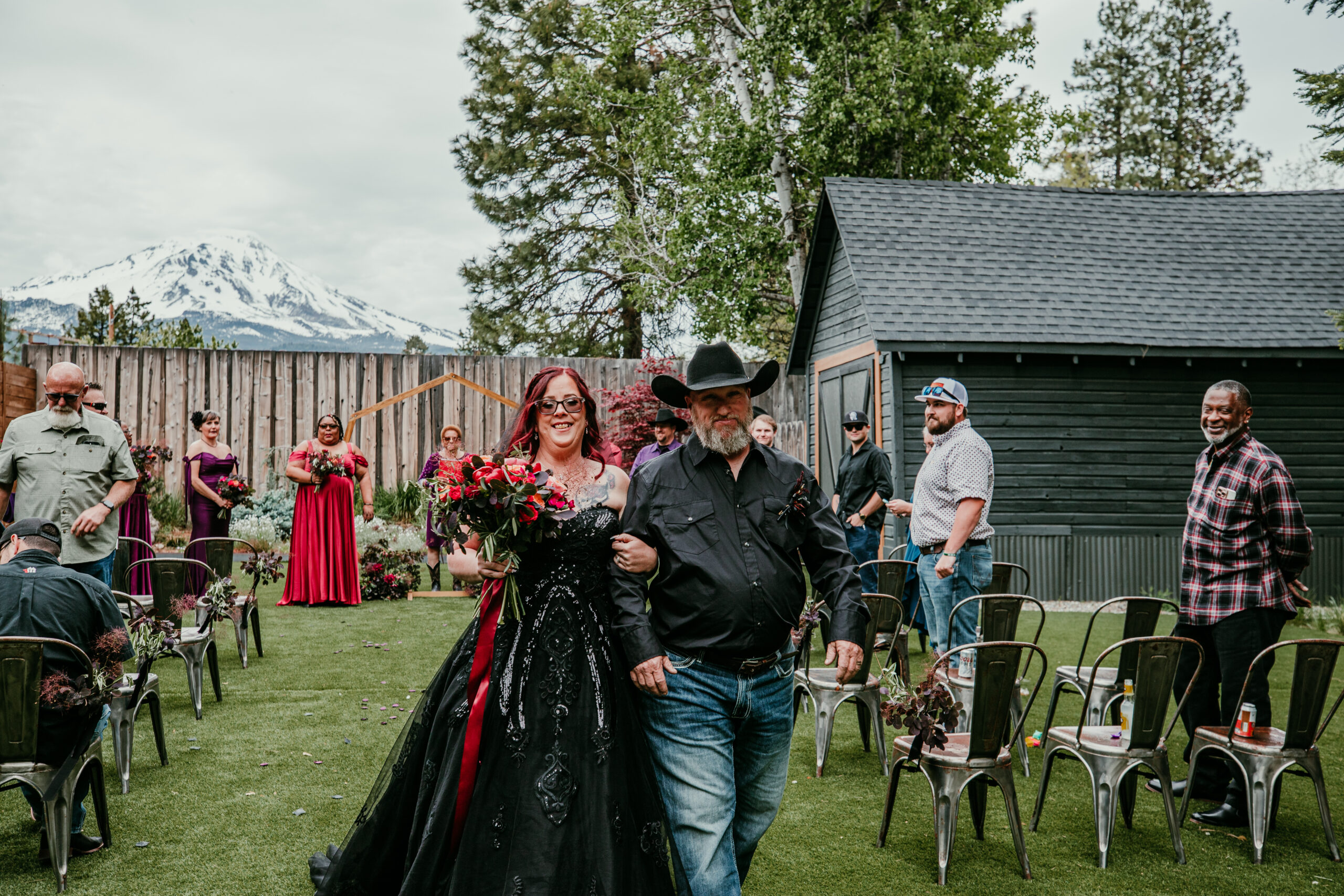 Bride and groom walking back down the aisle together after their ceremony while eloping in Mount Shasta, with guests cheering in the background.