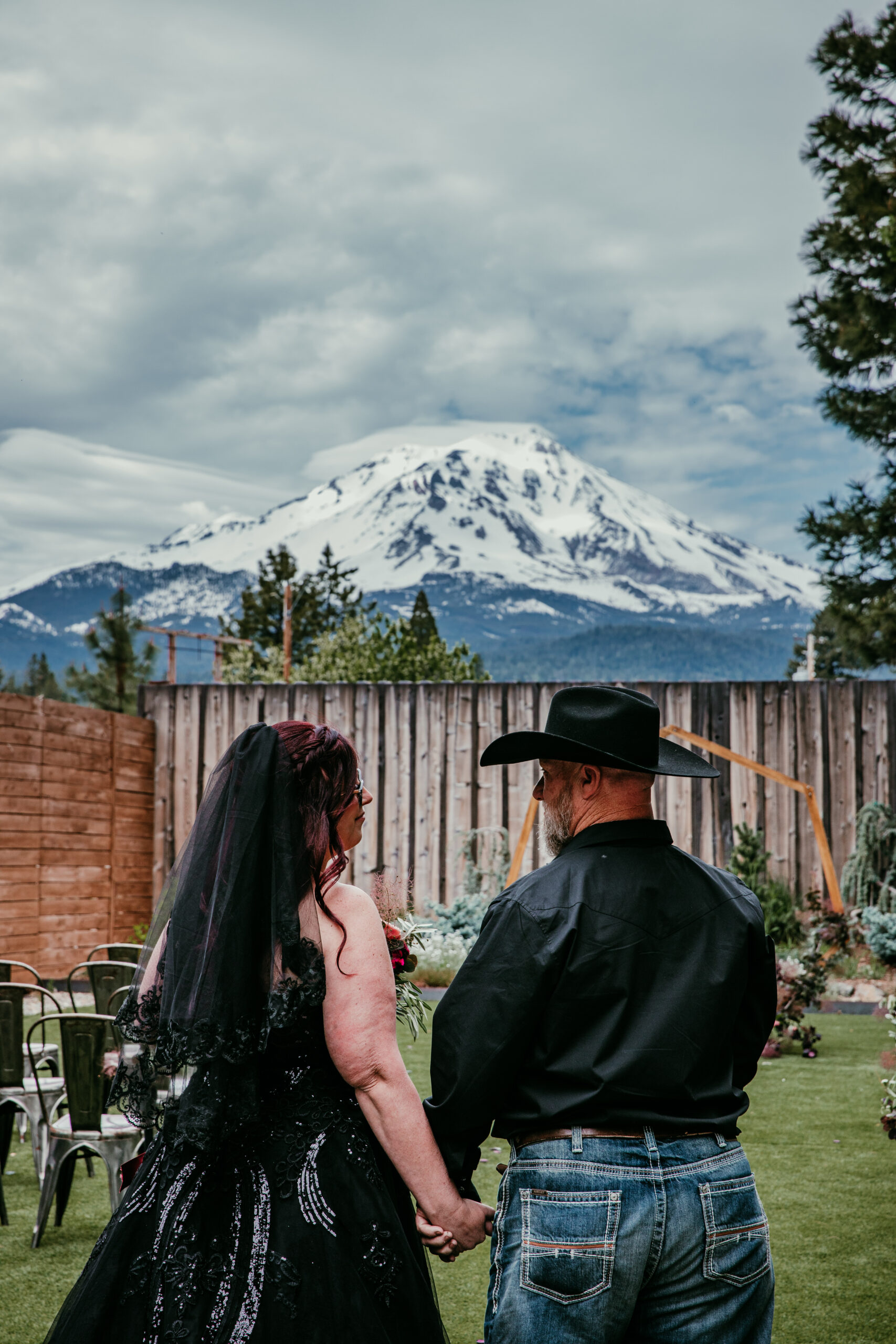 Bride and groom standing in front of a wooden ceremony arch with Mount Shasta in the background, one of the most romantic places to elope in California.