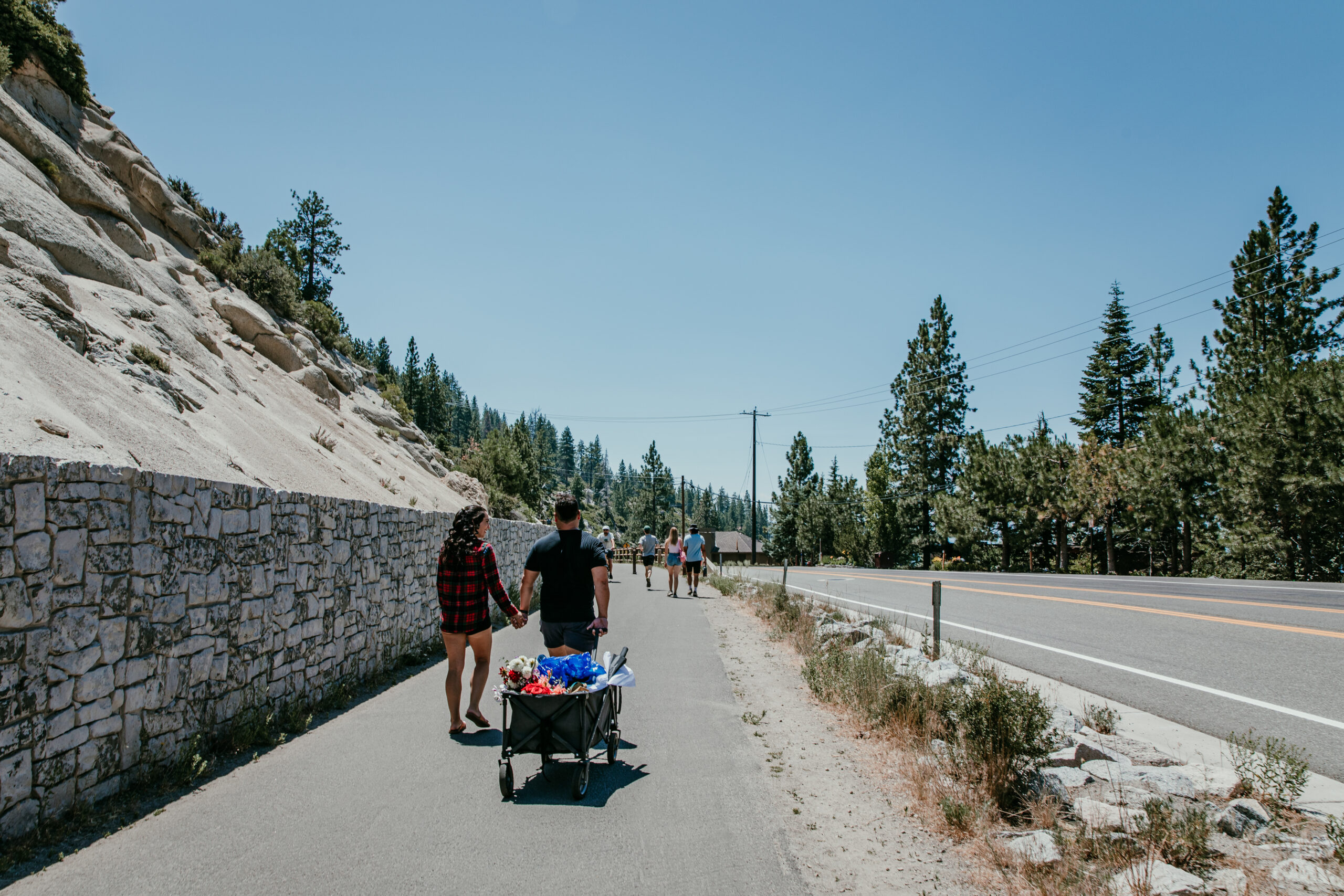 Couple walking hand-in-hand with a wagon of wedding items on their elopement in Lake Tahoe.