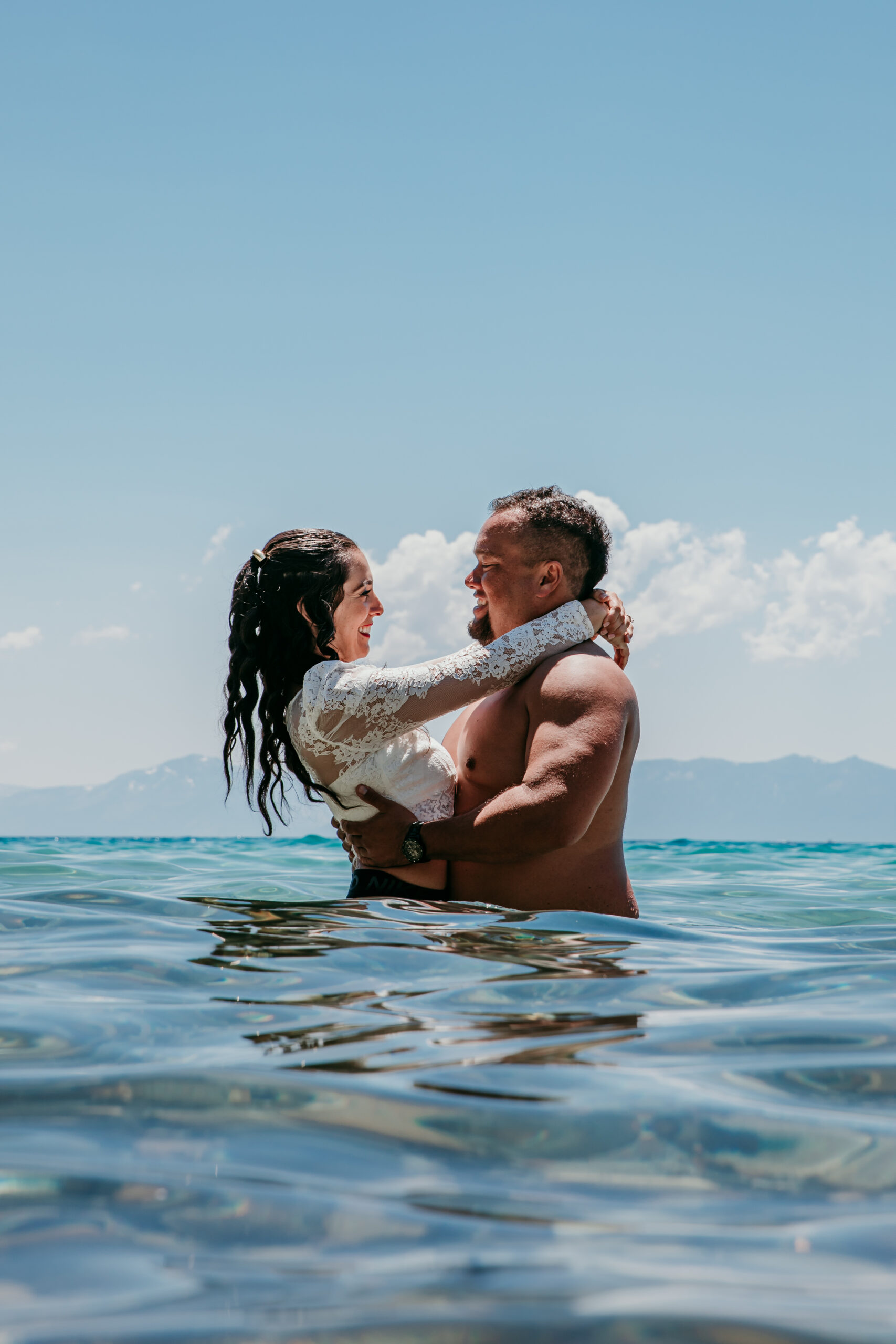 Bride and groom laughing together while swimming during their adventurous elopement in Lake Tahoe