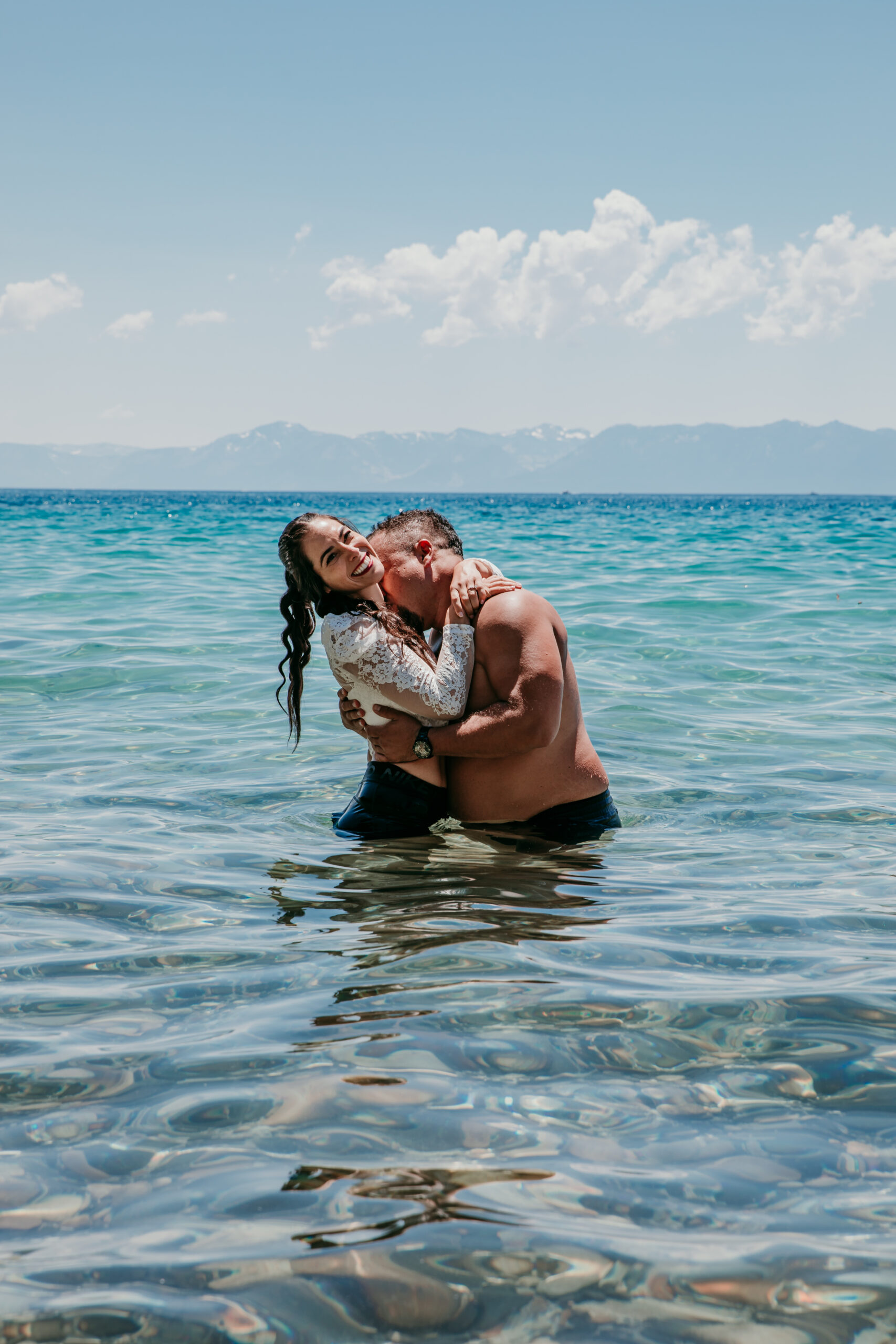 Bride and groom embracing and laughing while standing in the water during their elopement in Lake Tahoe.