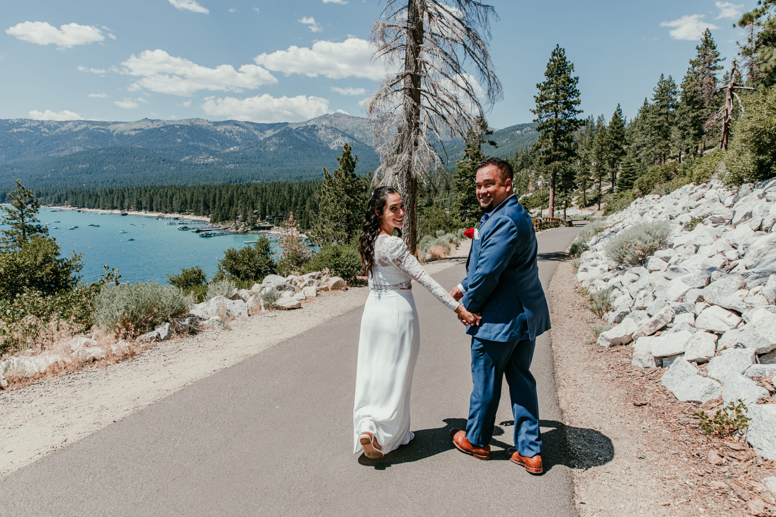 Bride and groom holding hands and smiling while walking near the lake during their elopement in Lake Tahoe