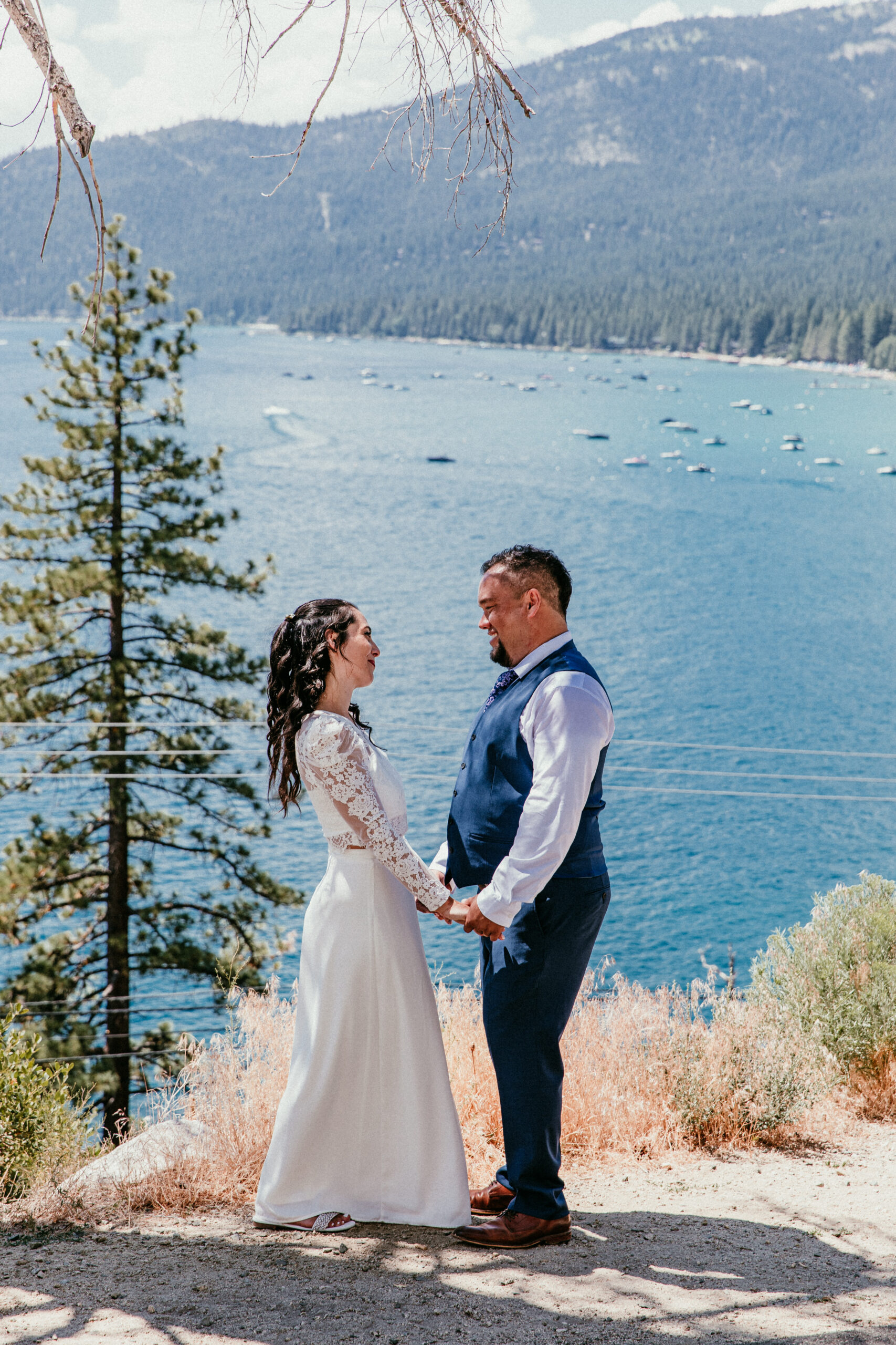 Bride and groom holding hands and smiling with Lake Tahoe in the background during their elopement.