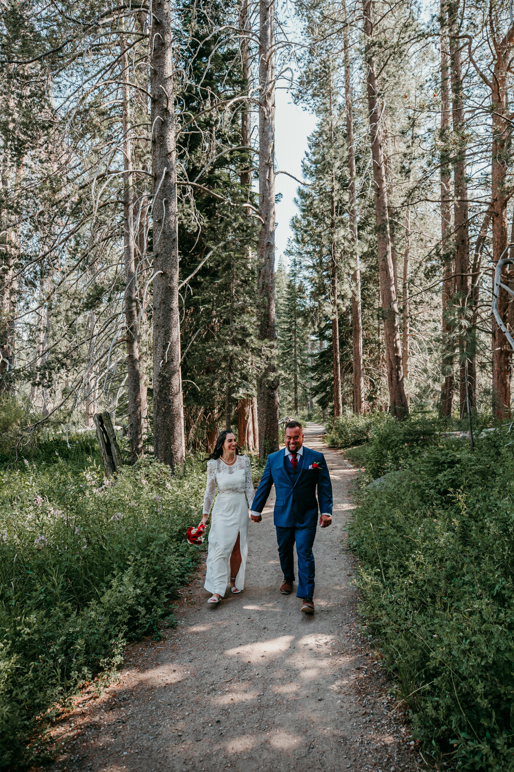 Bride and groom walking hand-in-hand through a forest path during their elopement in Lake Tahoe.
