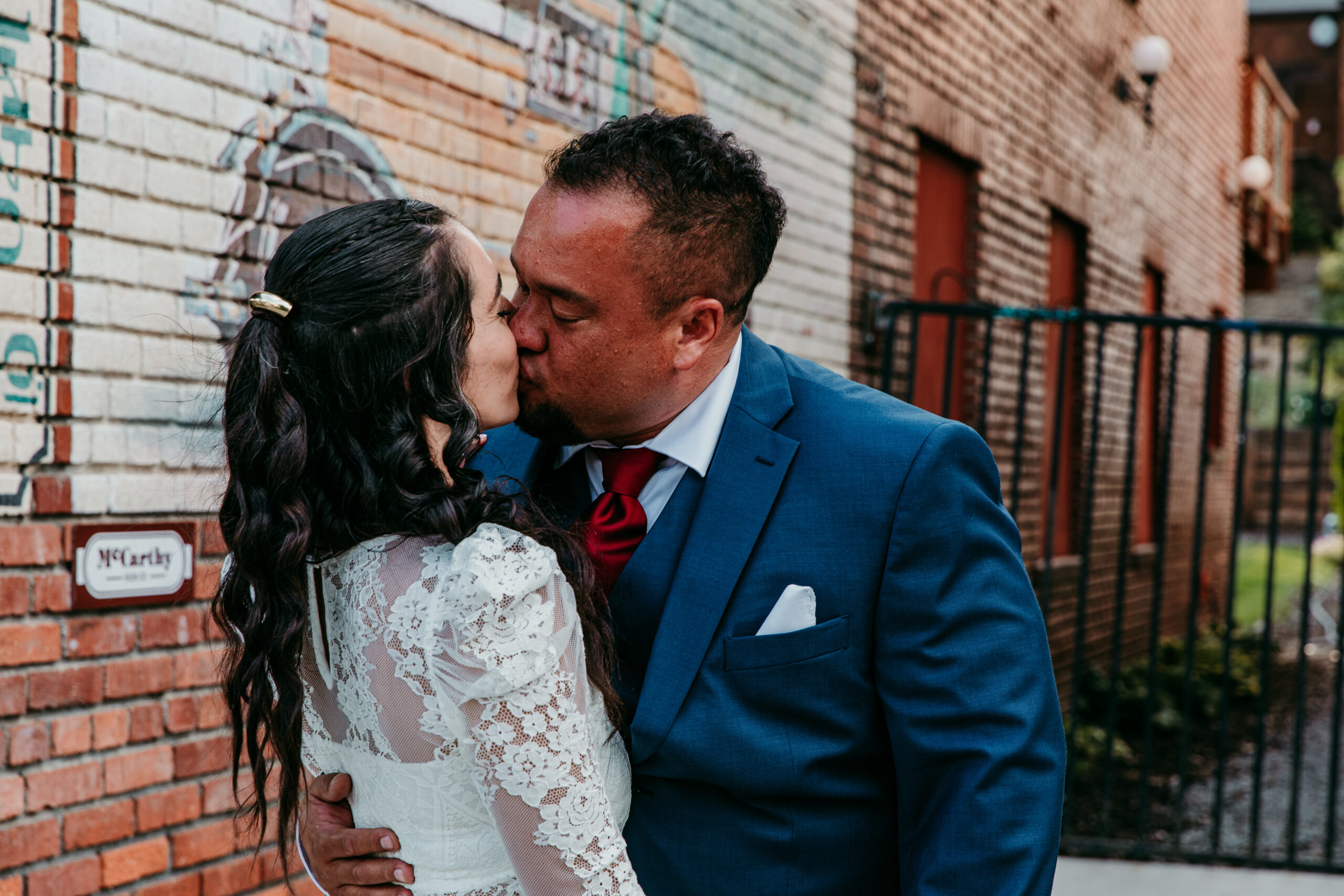 Bride and groom kissing against a rustic brick wall in downtown Truckee during their Lake Tahoe elopement.