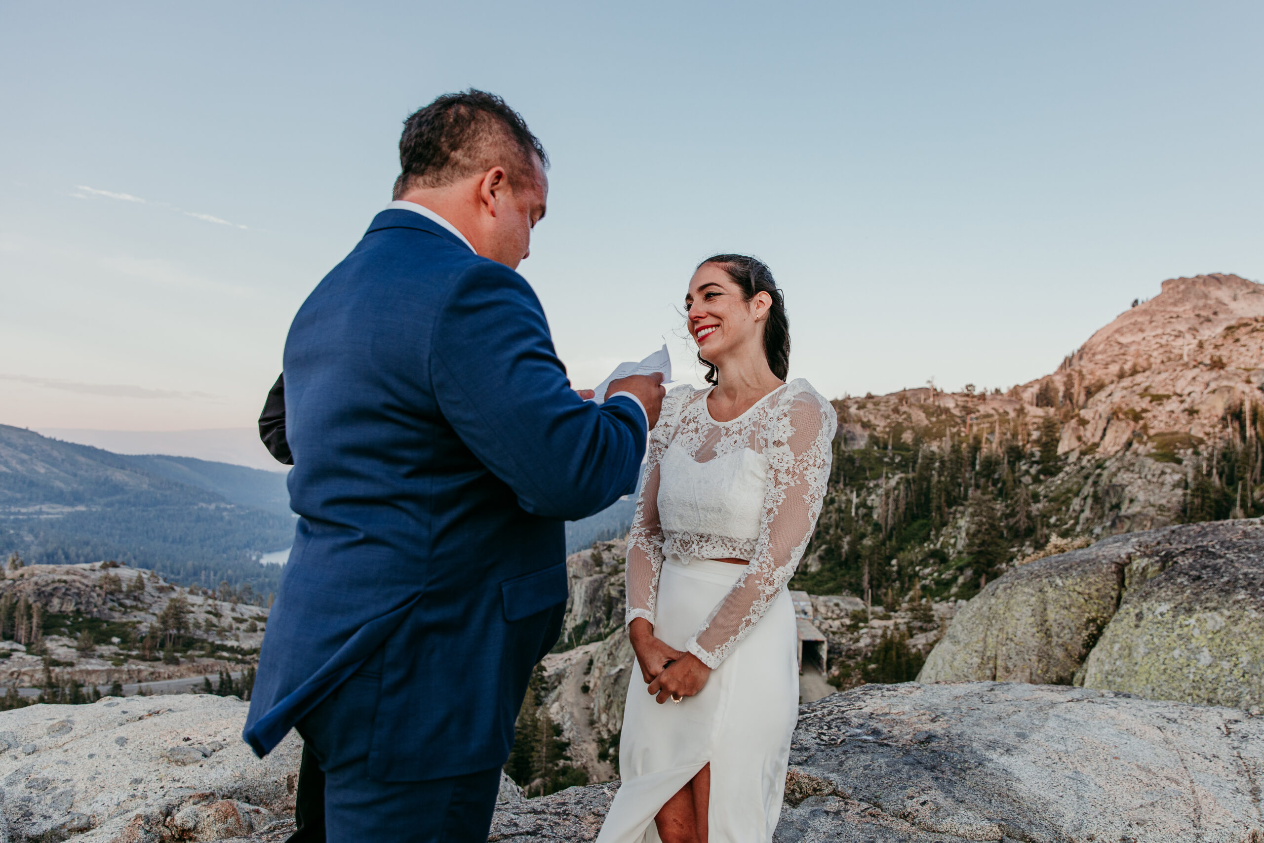 Elopement in Lake Tahoe with groom reading vows to the bride on a mountaintop during golden hour.