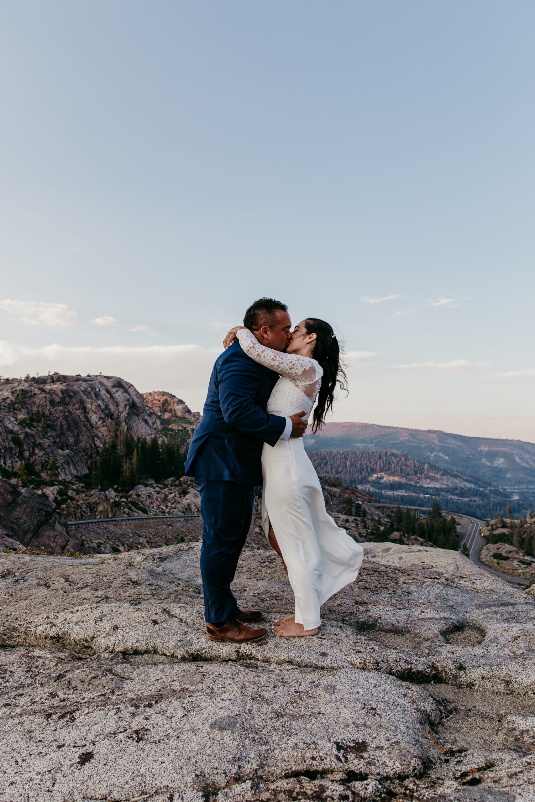 Elopement in Lake Tahoe with the couple sharing a kiss on a mountain ledge at sunset.