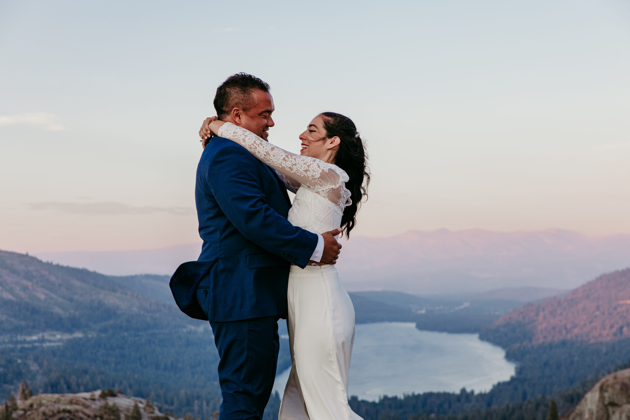 Elopement in Lake Tahoe couple embracing on a mountain overlooking the lake during sunset.