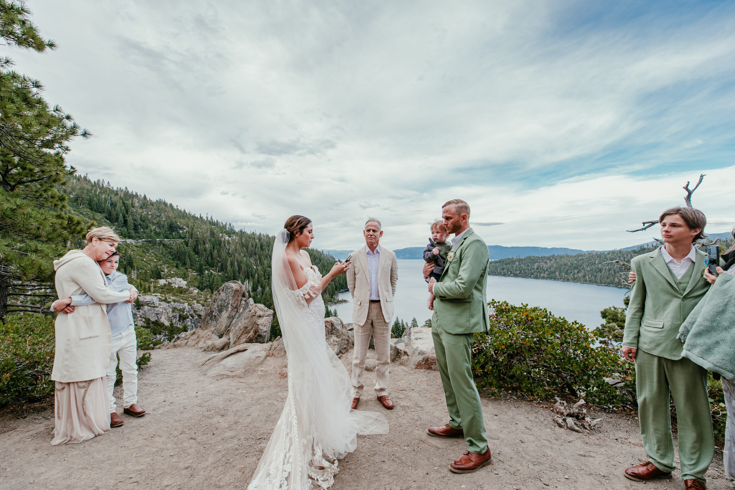 Couple exchanging vows with their family during an Emerald Bay elopement ceremony overlooking Lake Tahoe and the surrounding mountains.