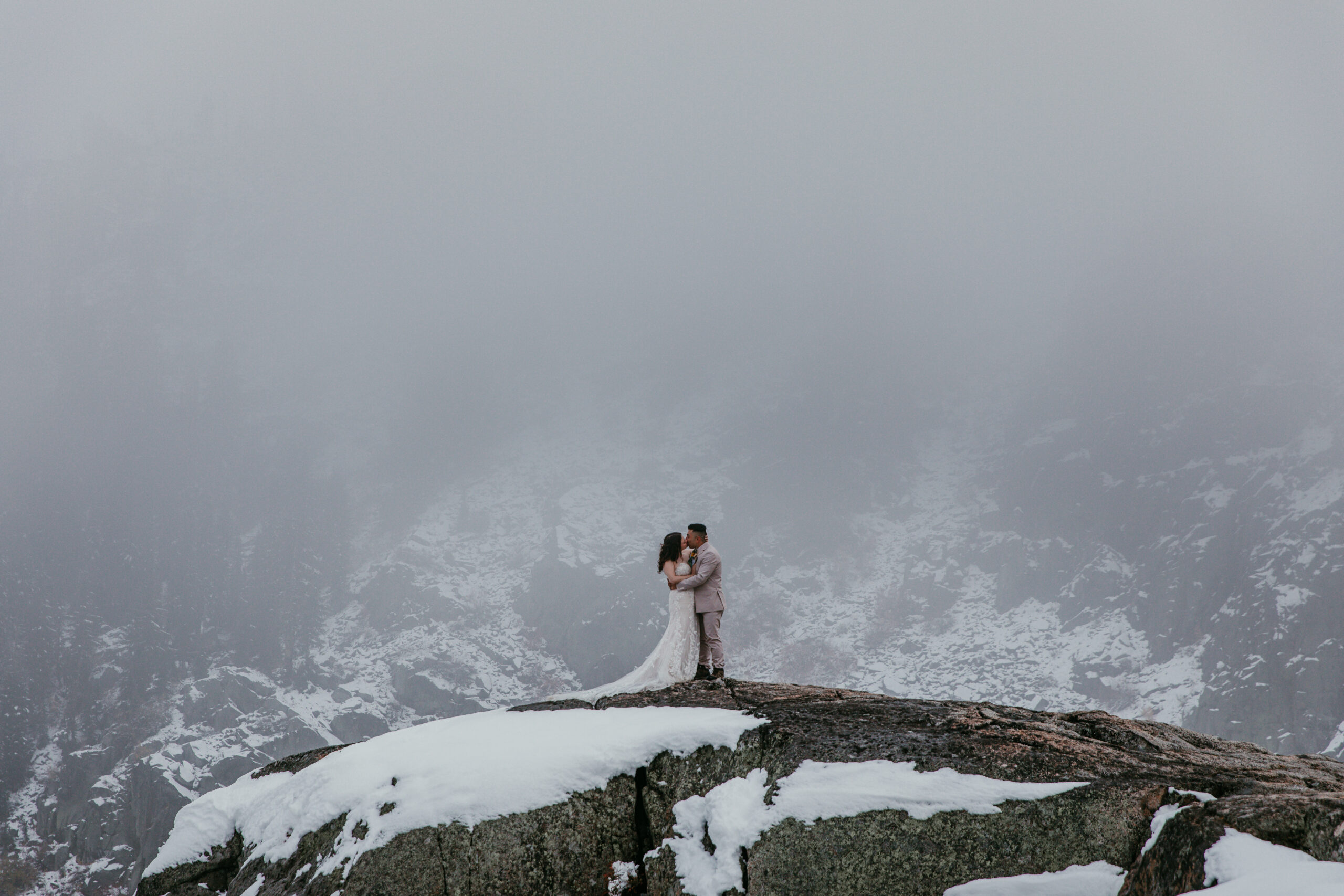 Couple standing on a snowy cliff during their Lake Tahoe winter elopement — Lake Tahoe elopement tips for adventurous couples embracing the weather.