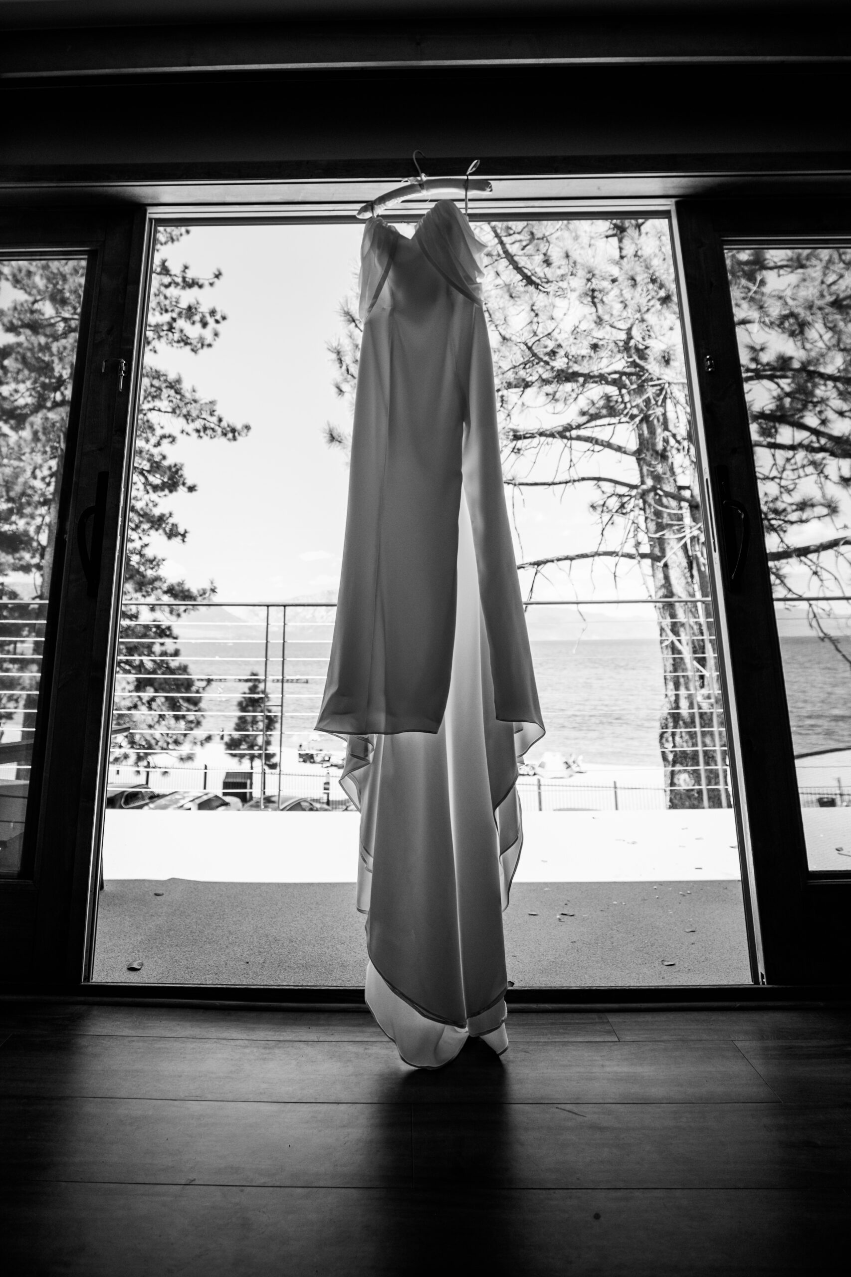 Wedding dress hanging in front of lake and pine trees at The Landing for an elopement Lake Tahoe.