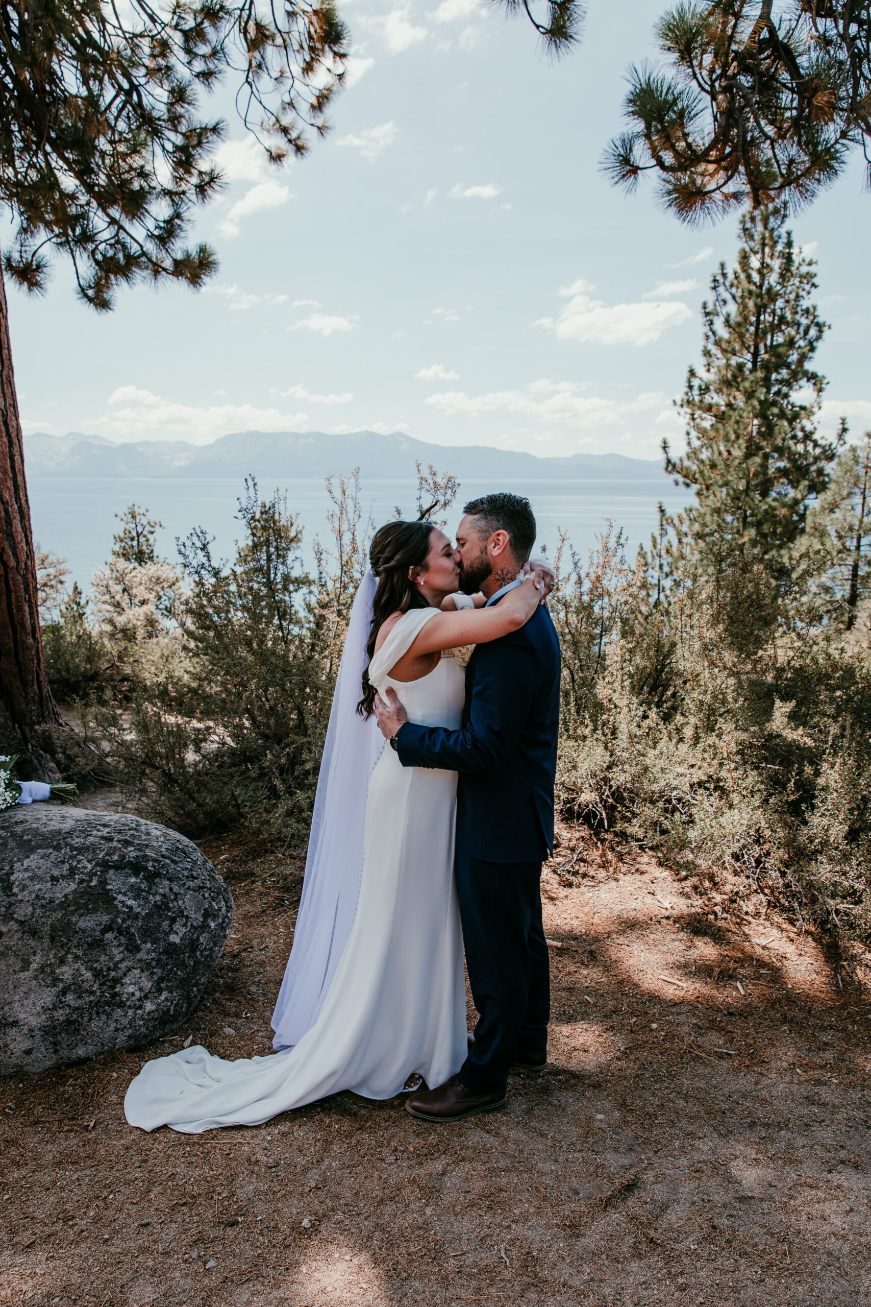 Bride and groom sharing their first kiss with lake views during their elopement Lake Tahoe ceremony.