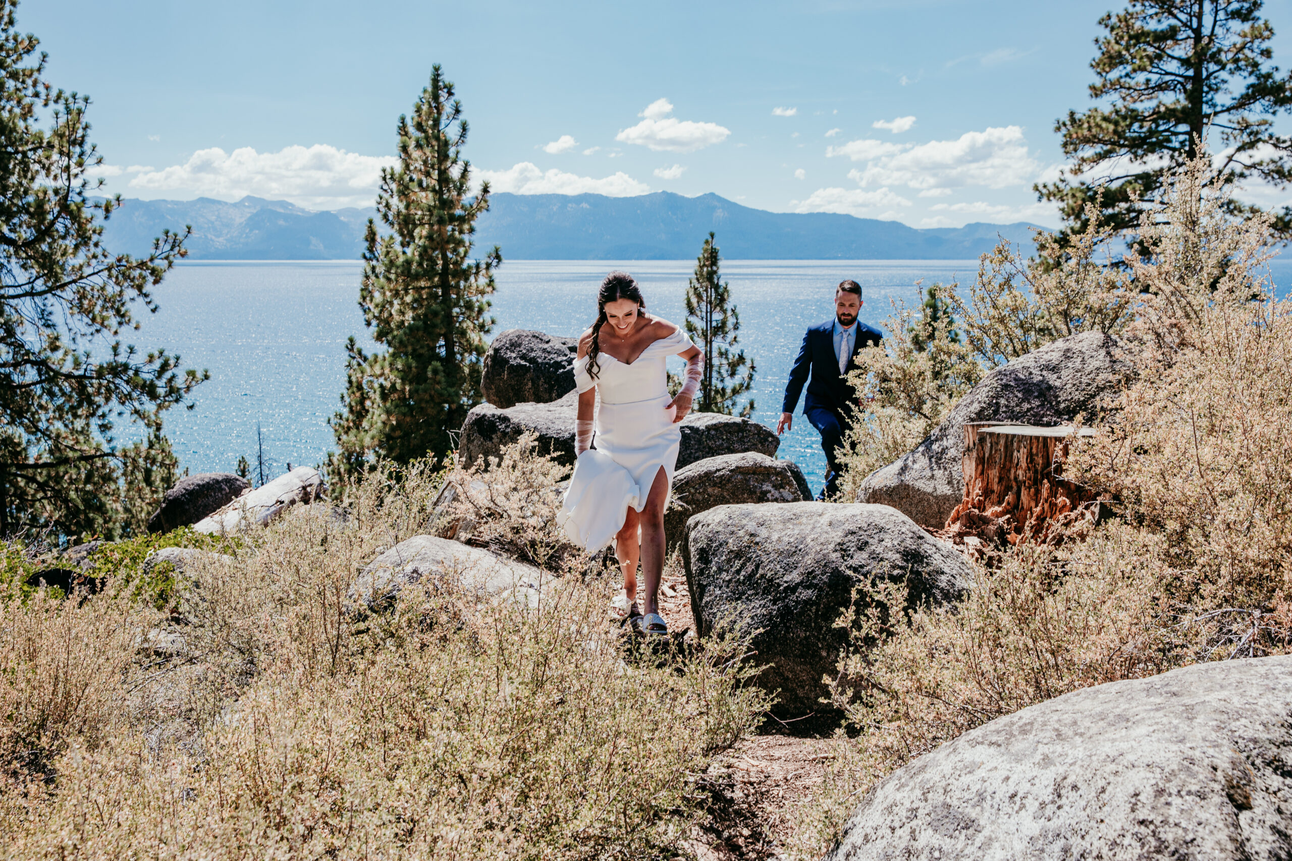Bride and groom climbing over boulders above the lake during their adventurous elopement Lake Tahoe.