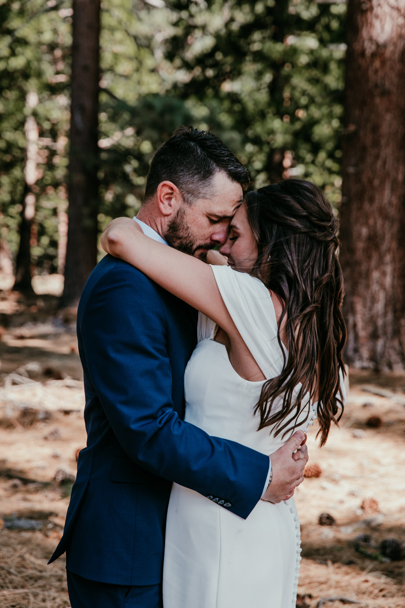 Couple hugging closely in the pine forest during their intimate elopement Lake Tahoe.