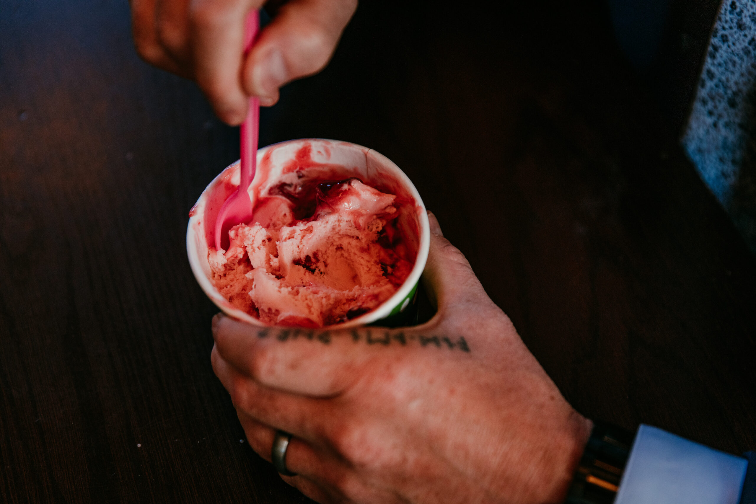 Close-up of groom enjoying strawberry ice cream during their elopement Lake Tahoe.