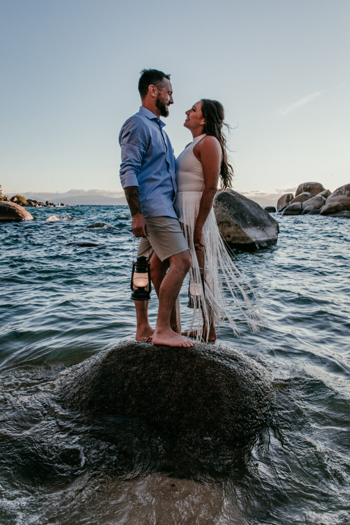 Couple standing together on a rock in the lake during golden hour showcasing unique elopement ideas in California