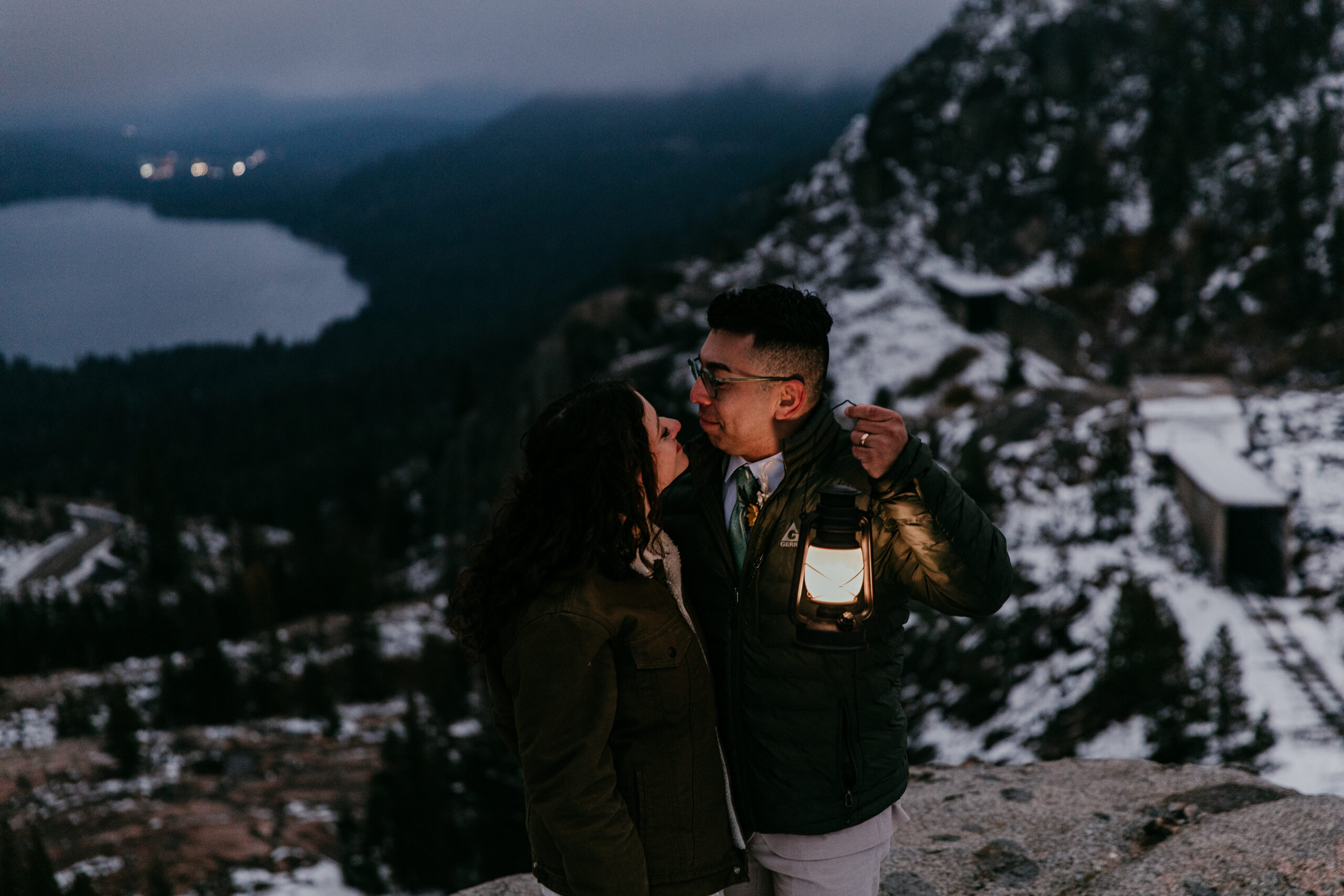 Couple holding a lantern on a snowy mountain overlook during their Lake Tahoe elopement, creating intimate lake tahoe elopement photos with dramatic alpine scenery
